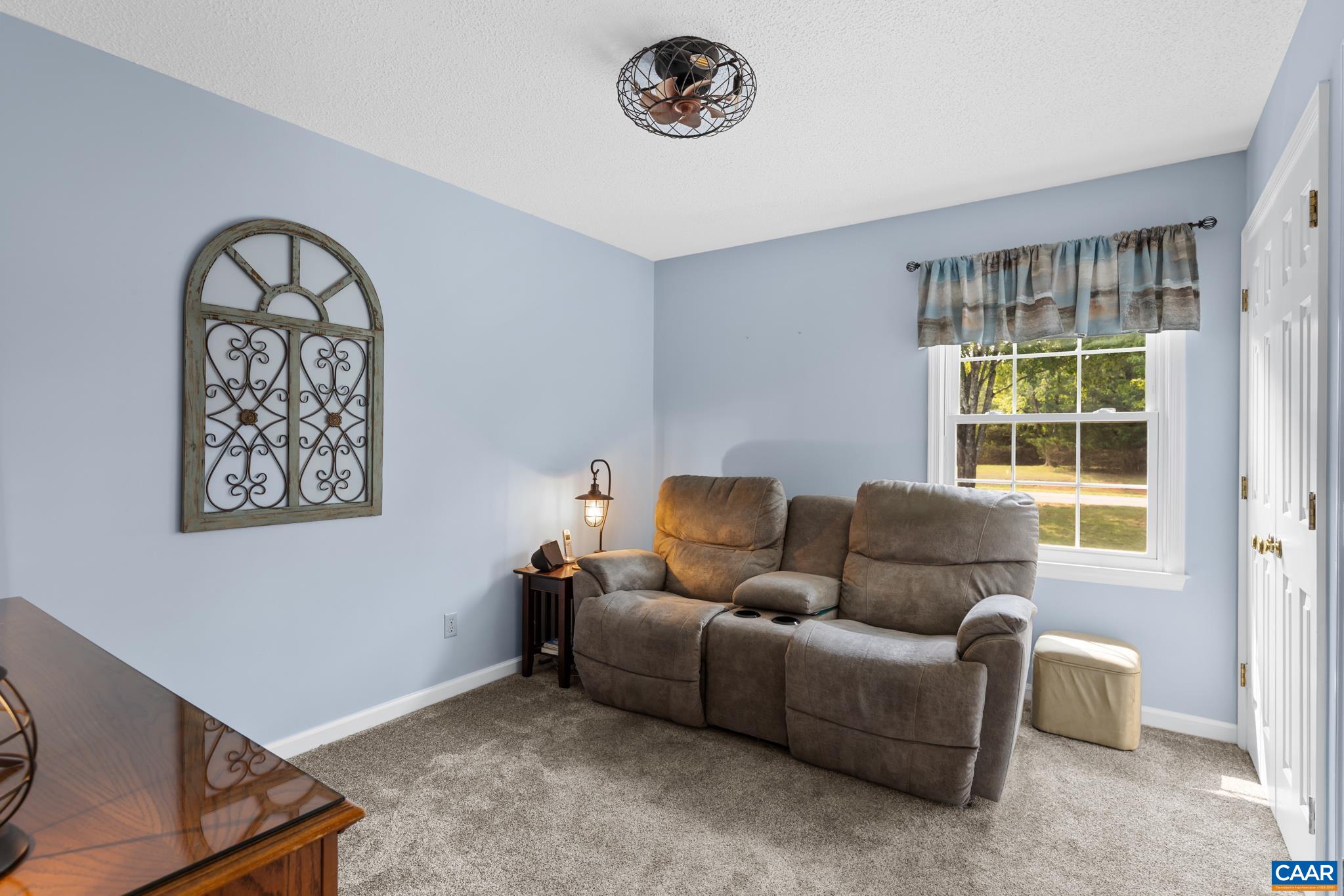 Relax in comfort in this serene sitting room! Highlights include light blue walls, cozy plush carpeting, and a bright window letting in plenty of natural light. A perfect spot to kick back!