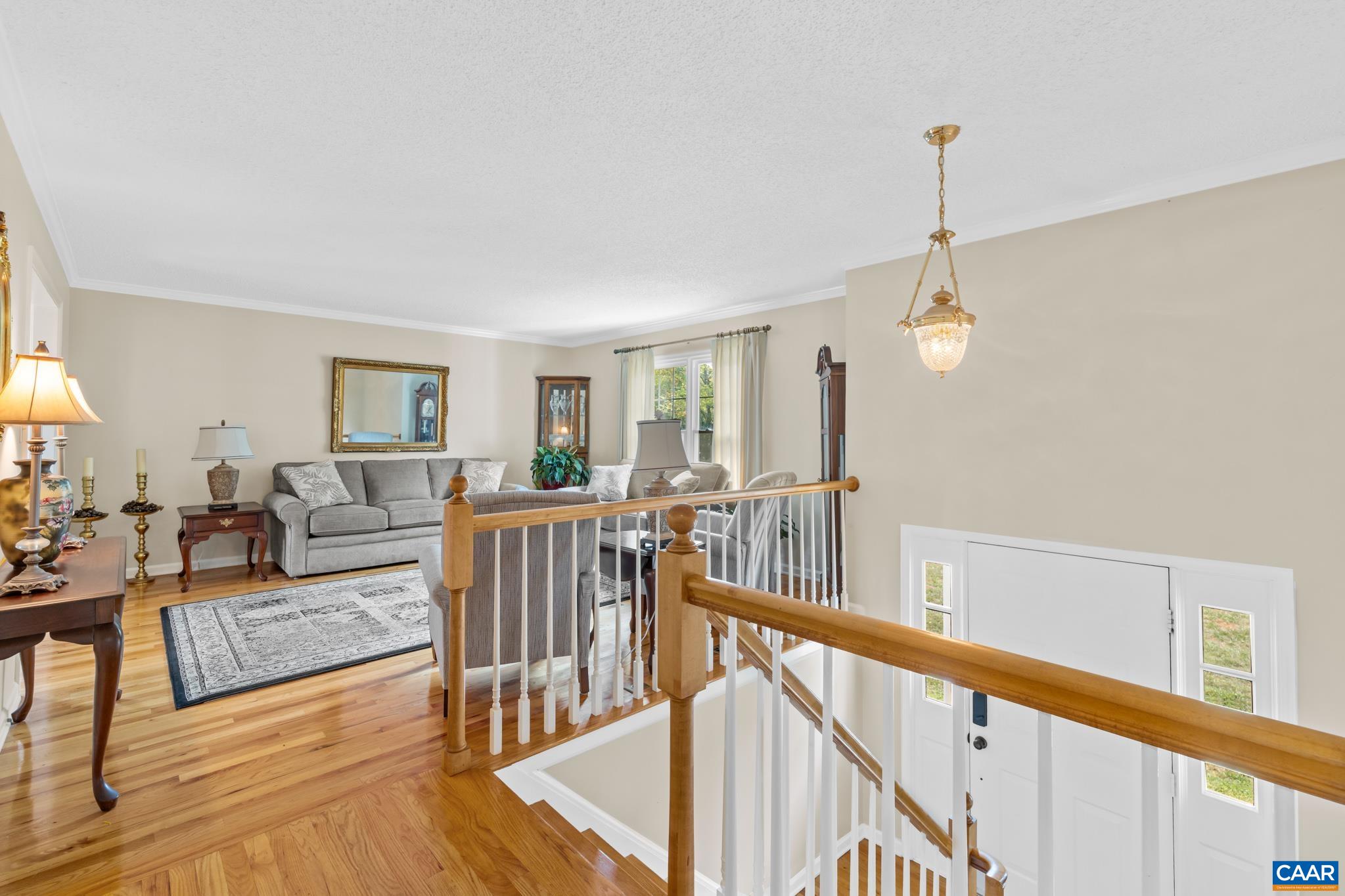 An open, light-filled entryway welcoming you home! Featuring gleaming hardwood floors, classic wood railings, and a seamless flow into the adjoining living room with elegant lighting and crown molding. Beautifully connected and full of charm!