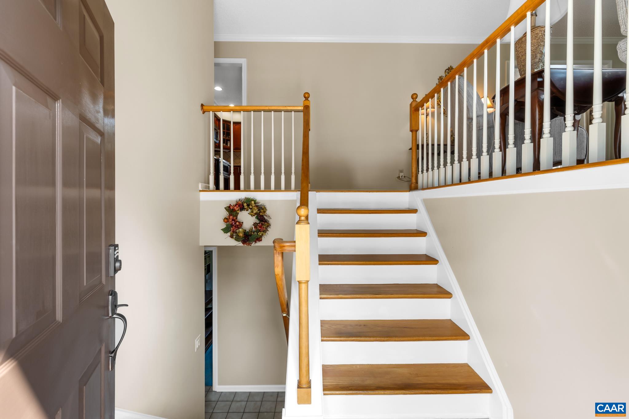Welcome guests into a bright and open entryway! Featuring classic wood-and-white railings, warm hardwood stairs, crisp white trim, and a split-level layout that flows seamlessly to upper and lower living areas. A warm, inviting welcome home!