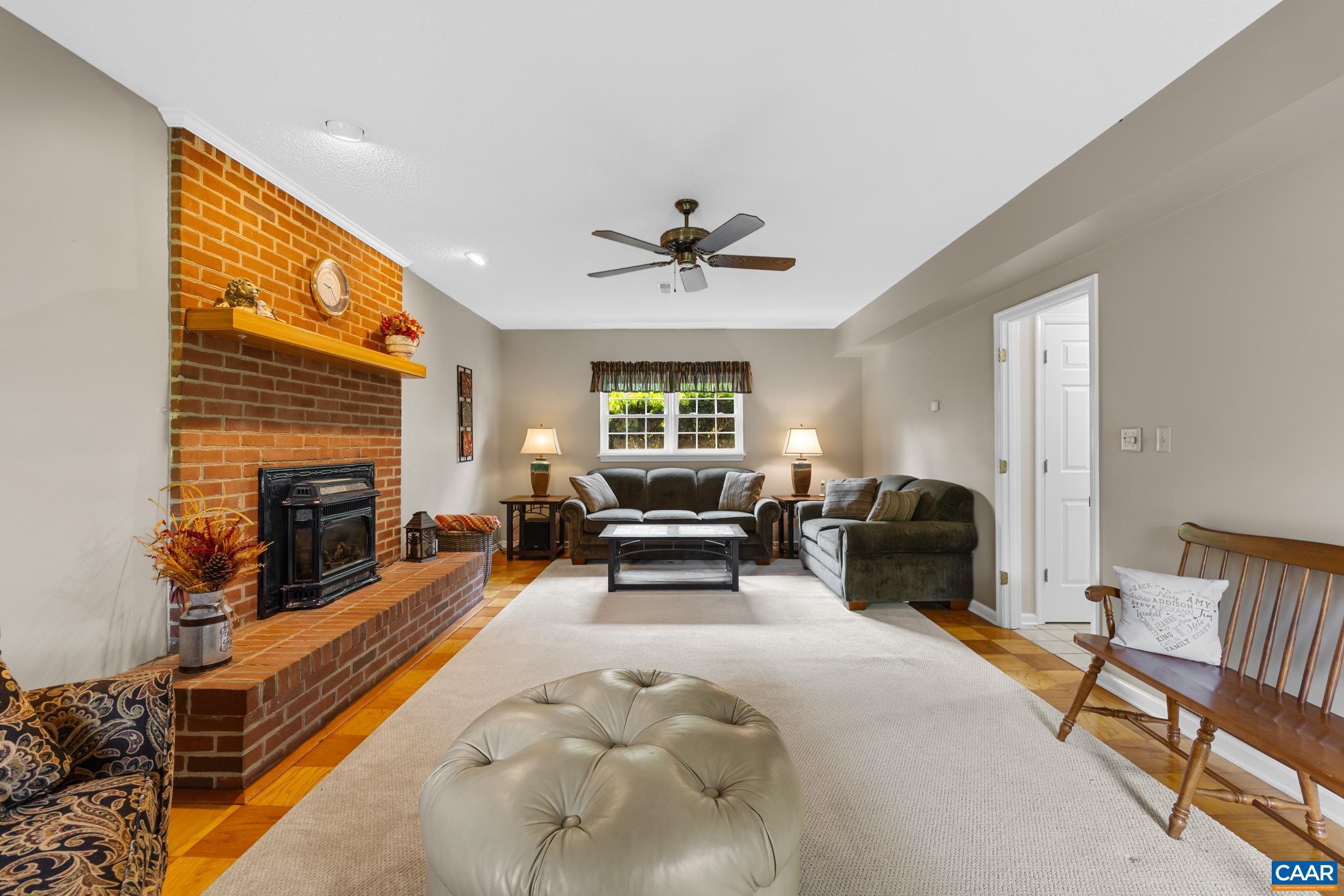 Unwind in this warm, inviting living space! Featuring a magnificent brick fireplace, stylish ceiling fan, and ample room to relax or entertain. Sunlight streams through the back window, making this spacious retreat truly feel like home!