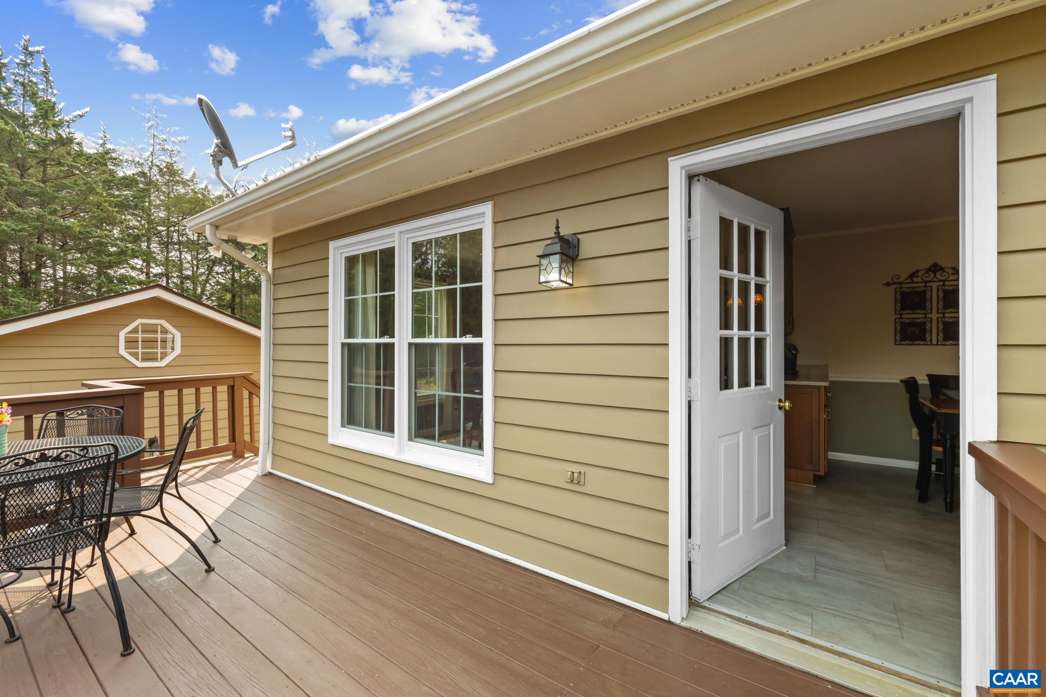 Effortless indoor-outdoor living! Step right out onto this spacious back deck, featuring room for outdoor dining, cypress siding with crisp white trim, and direct access to the interior. Ideal for relaxing, grilling, and entertaining!