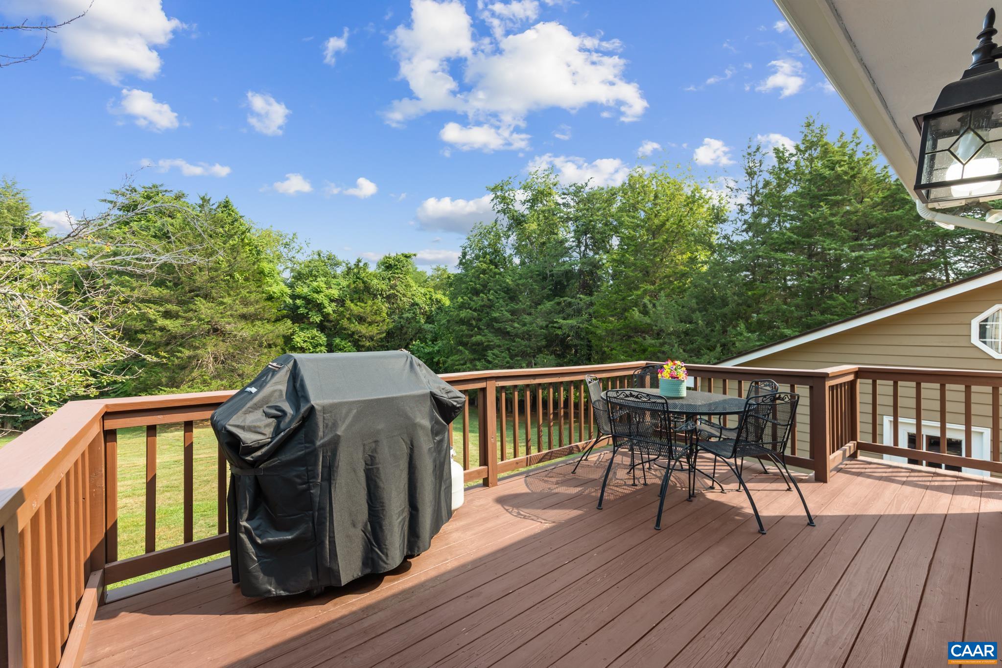 Soak in stunning sunny views from this broad outdoor deck! Complete with low-maintenance composite decking, classic wooden railings, space for a BBQ grill, and an outdoor dining area under blue skies. Ideal for summer hosting and relaxing!
