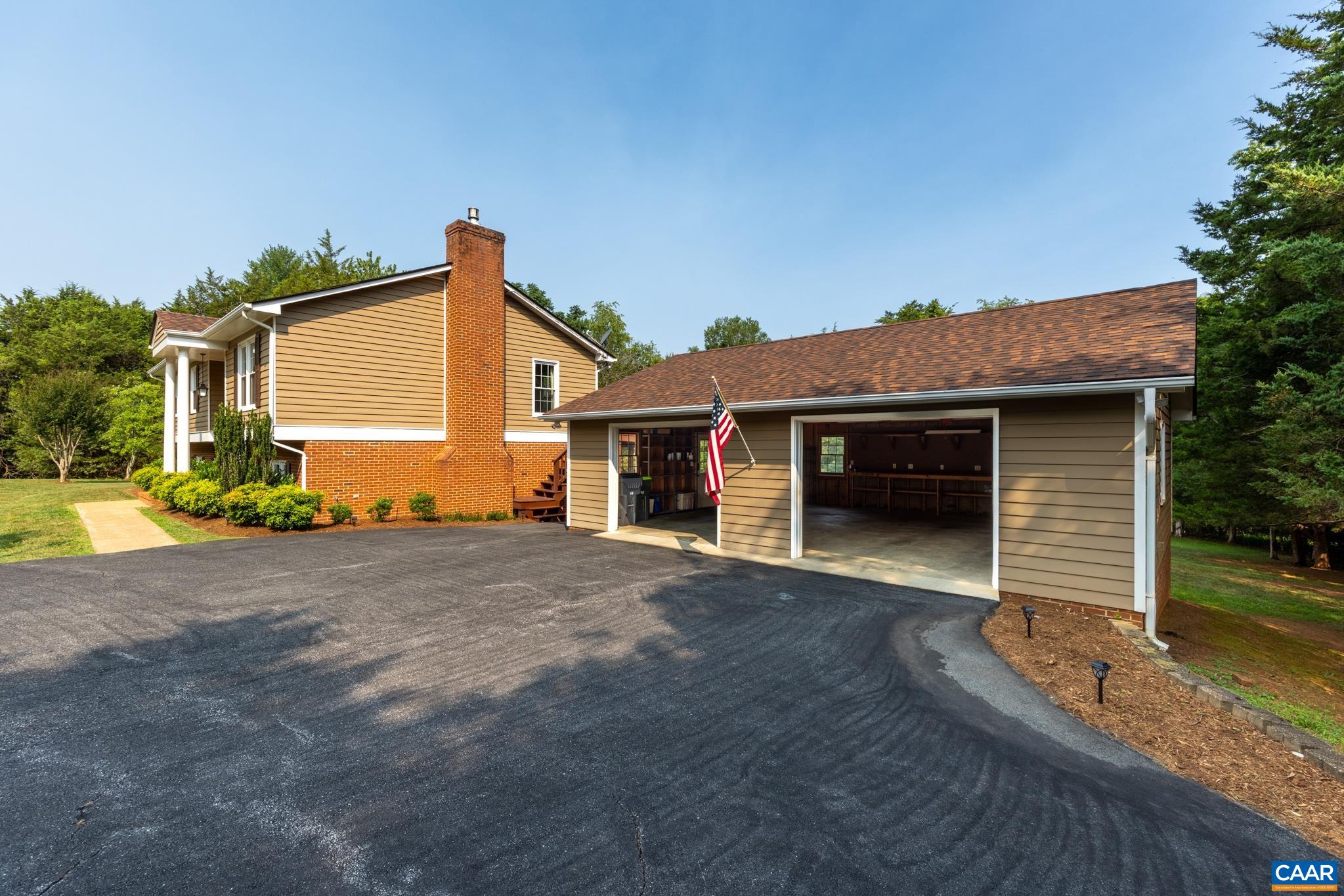 Impressive detached multi-car garage and workshop! Features a paved asphalt driveway, spacious open bays, durable cypress siding, and built-in shelving inside. Perfect for vehicle storage, hobbies, home projects, and extra equipment space!