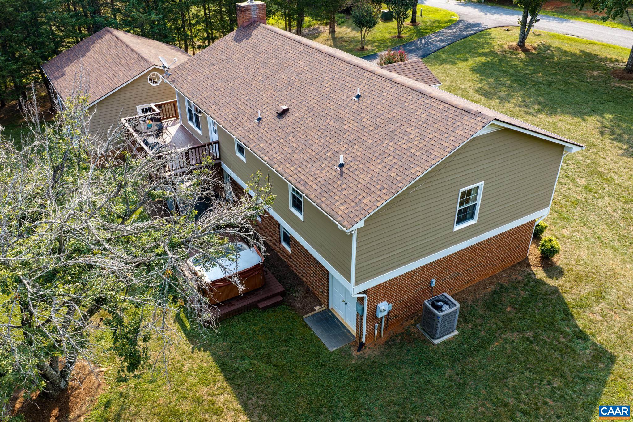 Breathtaking elevated view of this charming home! Features durable siding, classic brick lower accents, a spacious roofline (2020), a private outdoor deck with a hot tub, and a detached garage in the background. Private, picturesque living at its finest!