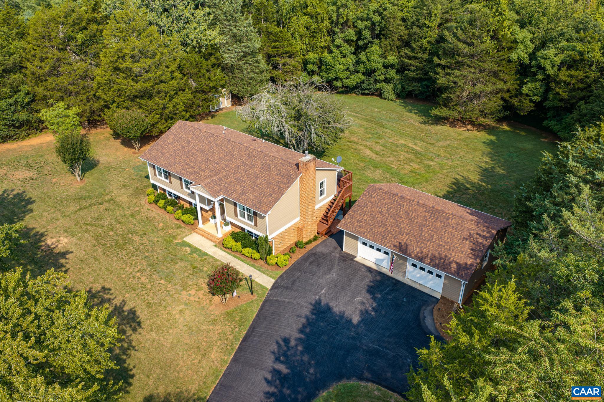 Private, picturesque country living at its finest! Stunning aerial view showcasing a well-maintained home, expansive paved driveway, and a spacious detached garage/workshop, all surrounded by lush mature trees and a sprawling green lawn!