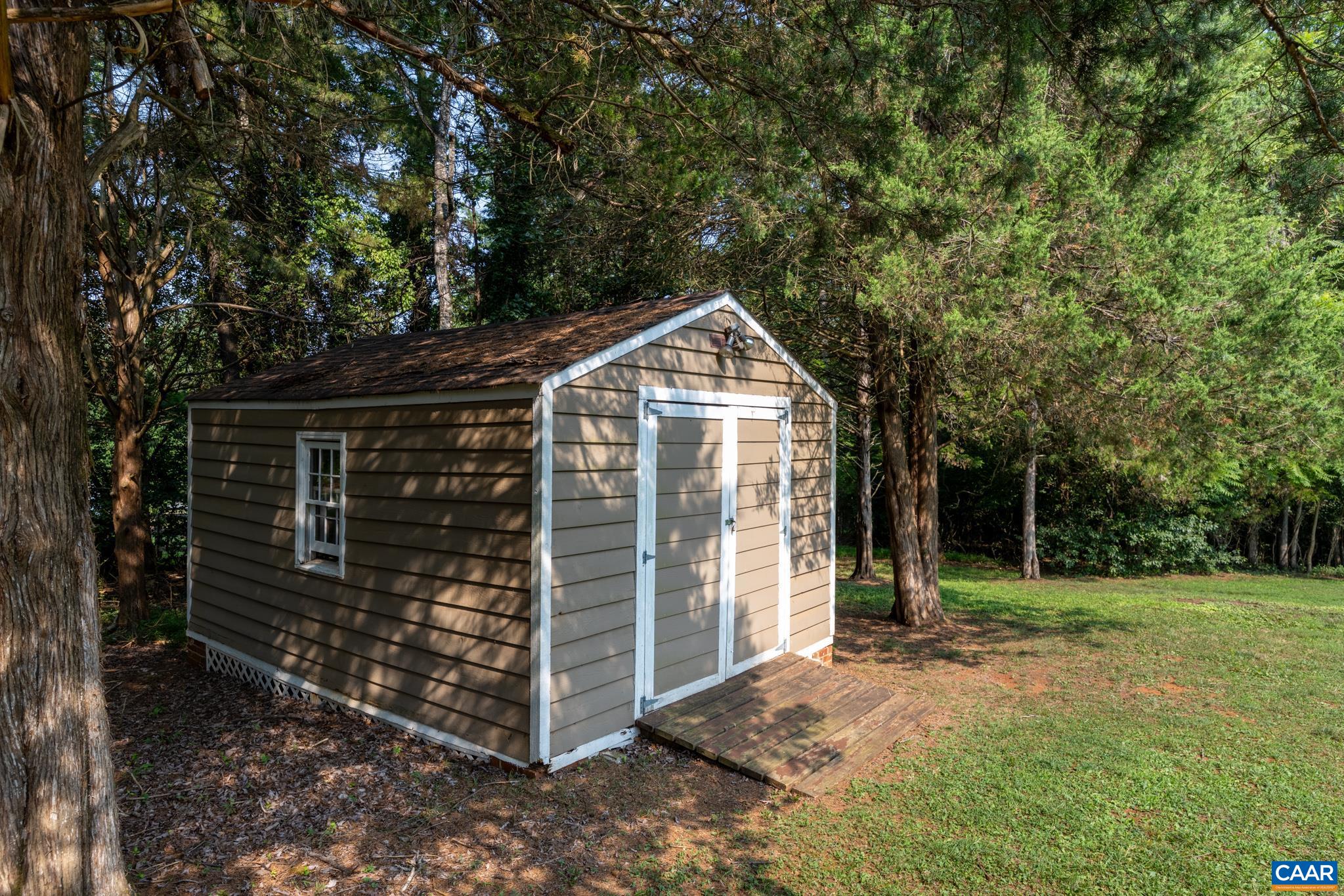 Convenient detached storage shed nestled in a peaceful, tree-lined backyard! Features durable siding, double front doors with an access ramp, and a side window. Ideal for housing lawn equipment, tools, bikes, and extra outdoor gear!