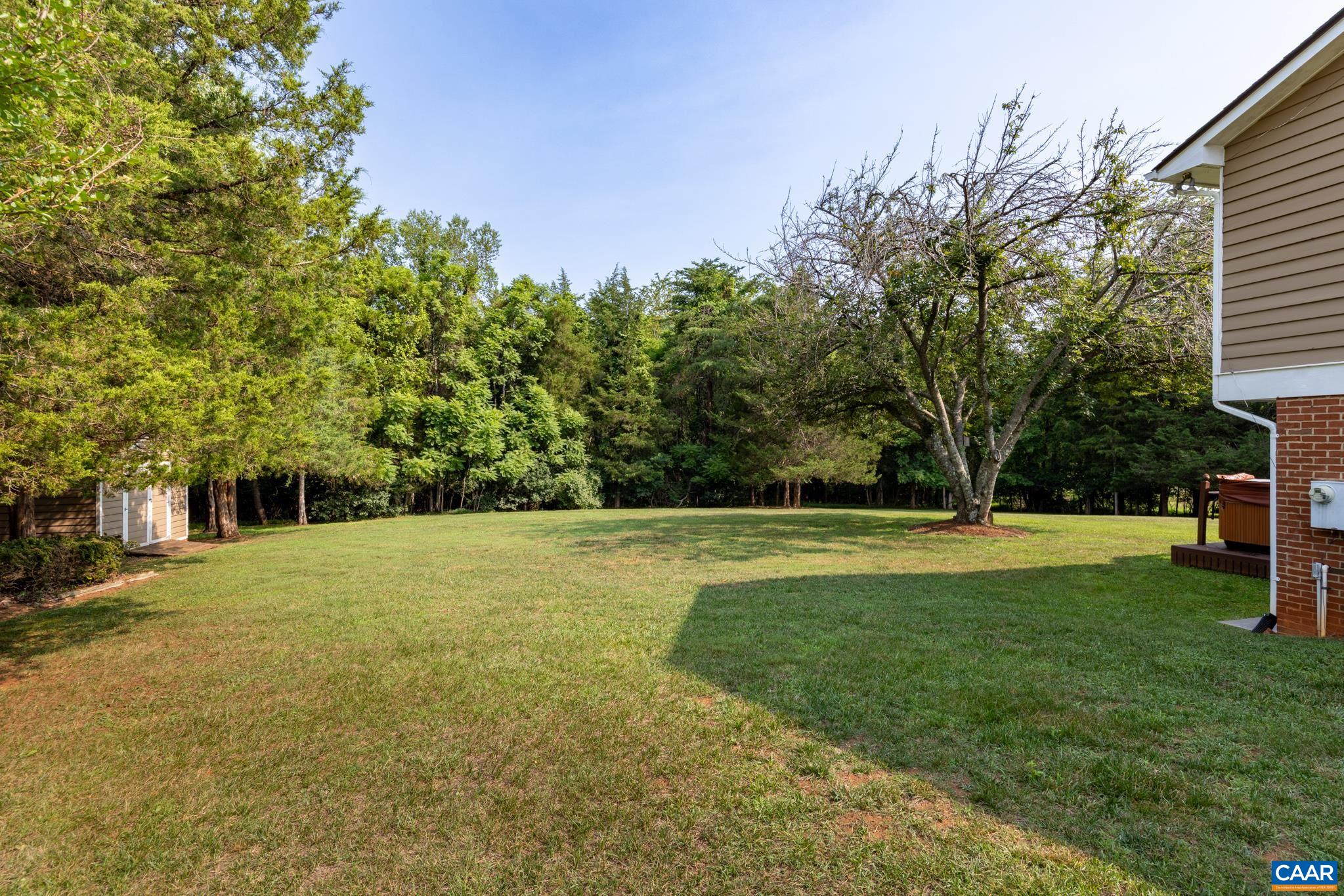 Expansive, sun-drenched yard surrounded by mature, lush green trees! Offers endless space for lawn games, pets, gardening, or future outdoor additions, plus a small shed tucked in the trees. Perfect for private outdoor living and play!