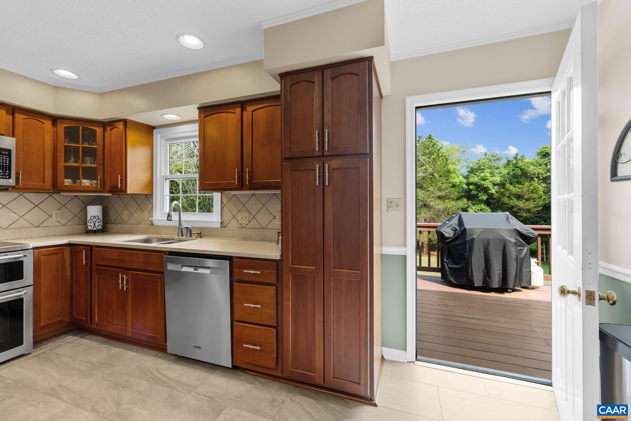 Step right out to outdoor living! This lovely kitchen features rich wood cabinetry, modern stainless appliances, and direct access through a glass door to a spacious back deck—perfect for summer barbecues and seamless indoor-outdoor entertaining!