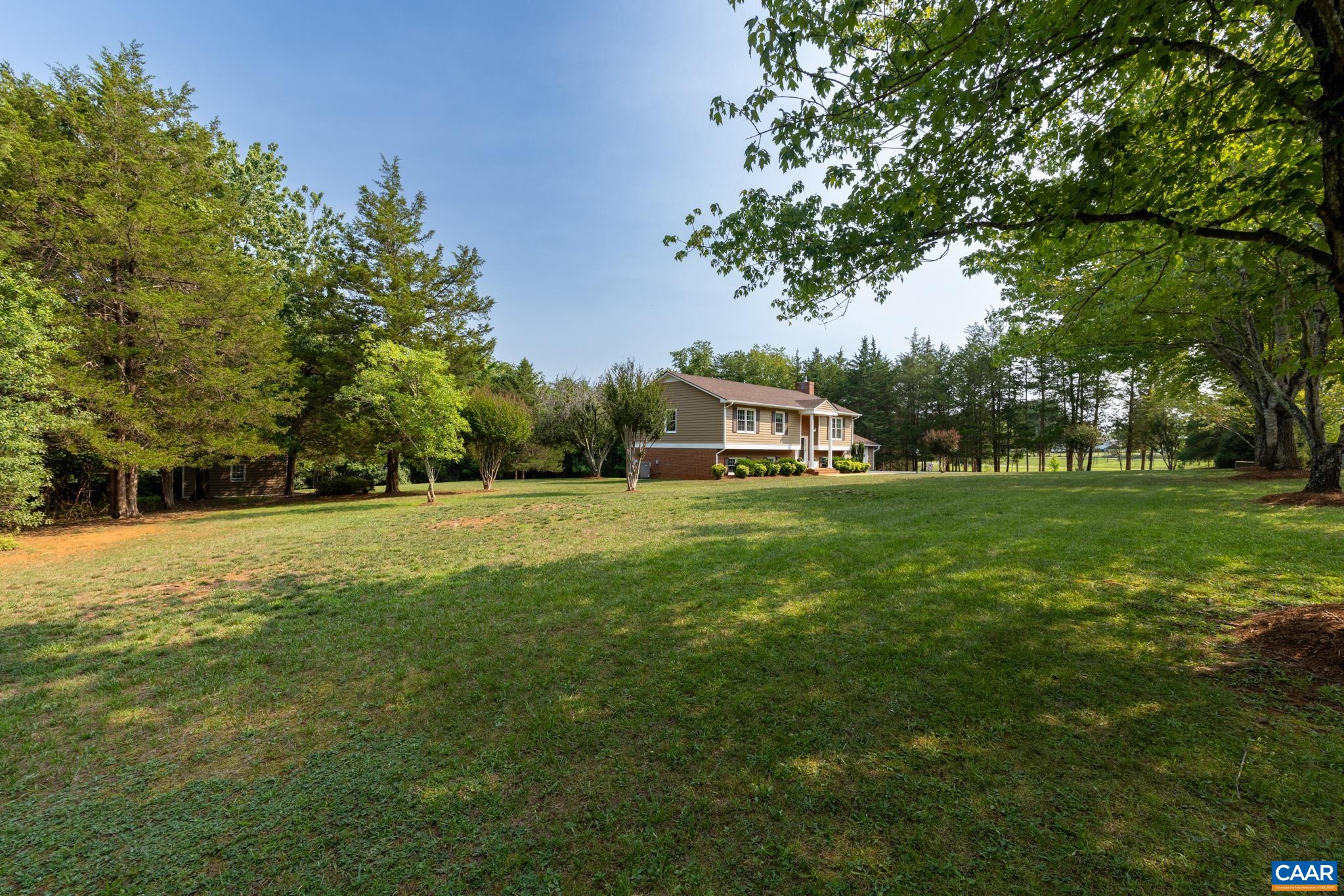 Sprawling, lush green lawn surrounded by majestic, shade-providing trees! Offers endless room for outdoor activities, pets, and gardening, with a picturesque view of the home nestled in the background. A private, tranquil backyard retreat!