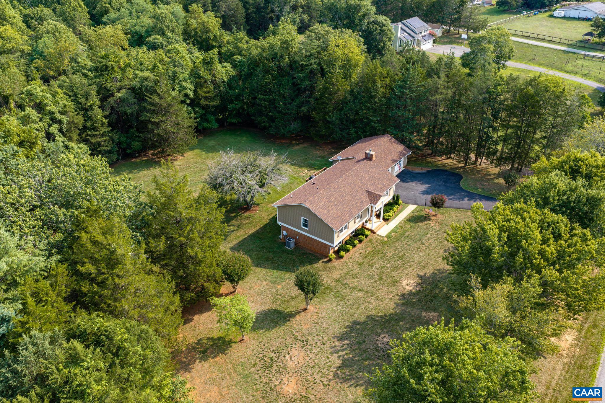 Stunning high aerial view of this private countryside estate! Nestled among lush green woods, featuring a vast lawn, paved driveway, detached garage, and total privacy. The ultimate peaceful retreat with endless room to enjoy!