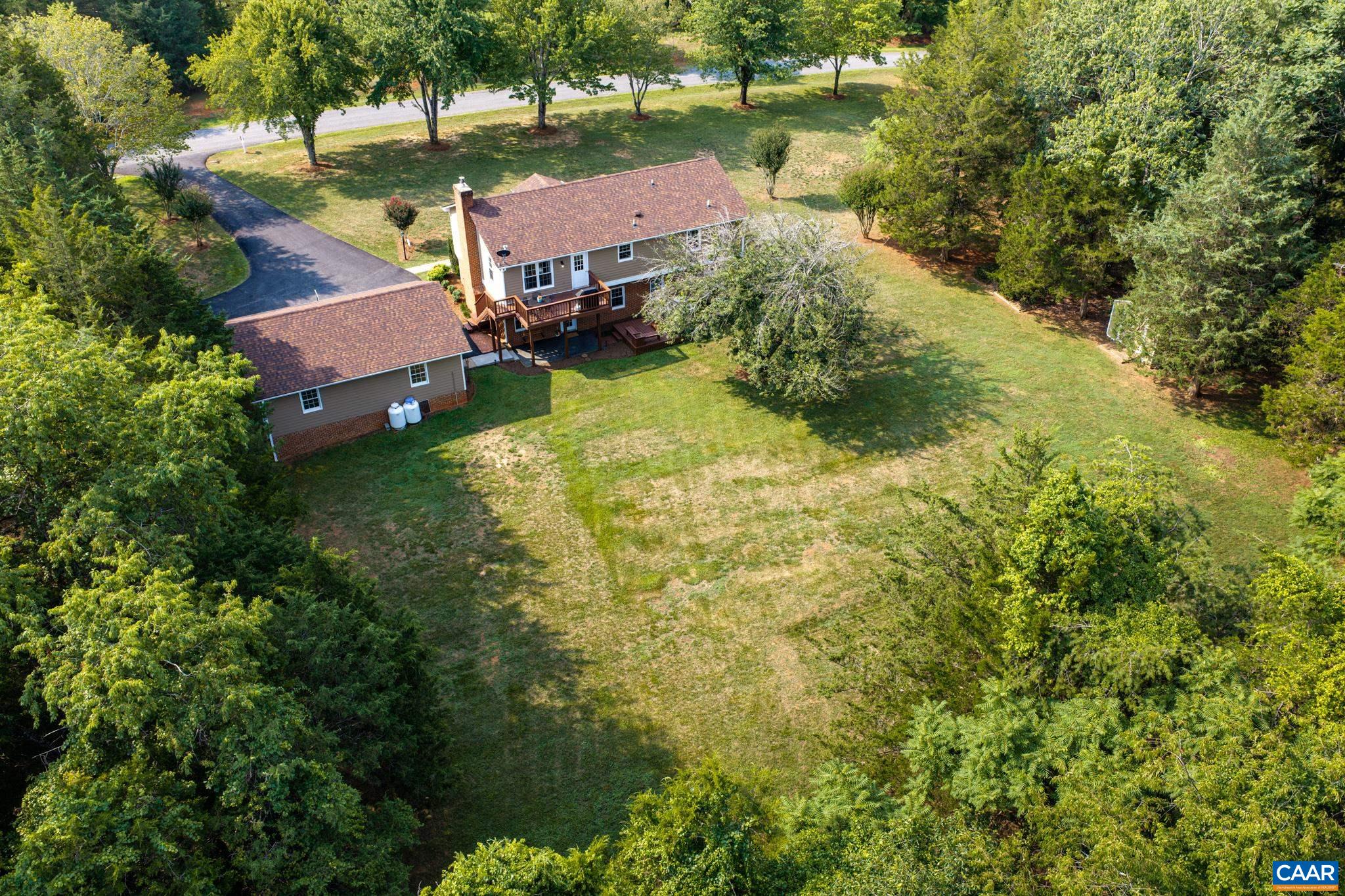 Breathtaking aerial view highlighting this private countryside haven! Features a sun-drenched, sprawling lawn bordered by lush trees, a spacious back deck, and an expansive paved driveway. Exceptional privacy and room to spread out!