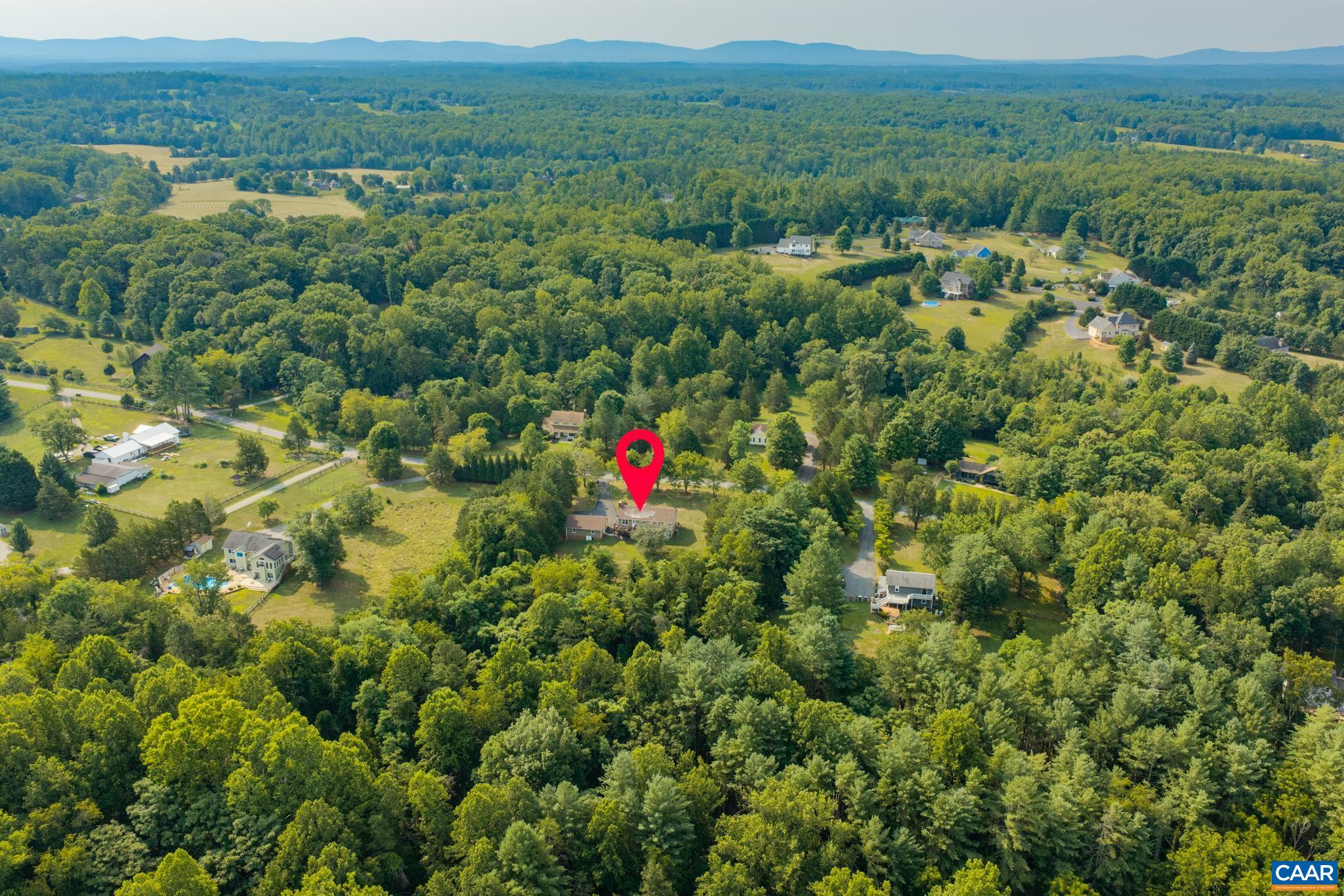 Stunning high-altitude aerial view pinpointing the property location! Surrounded by dense green woodlands, rolling hills, and blue mountain vistas in the distance. An exceptional private haven tucked away in nature's scenic beauty!