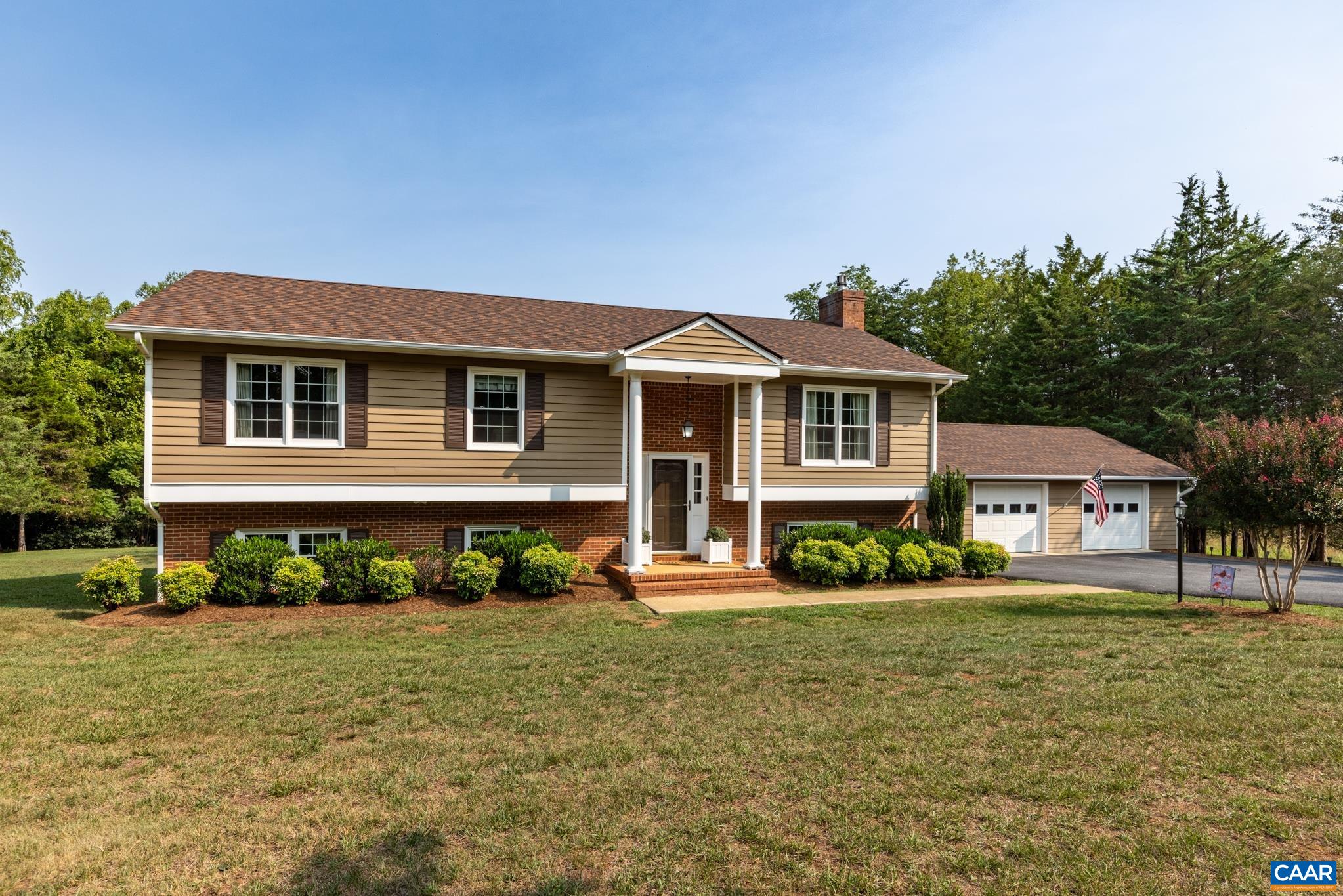 Charming split-foyer home with irresistible curb appeal! Highlights include a well-manicured lawn, brick-accented exterior, covered portico entry, and a spacious detached multi-car garage, all in a peaceful, tree-lined setting!