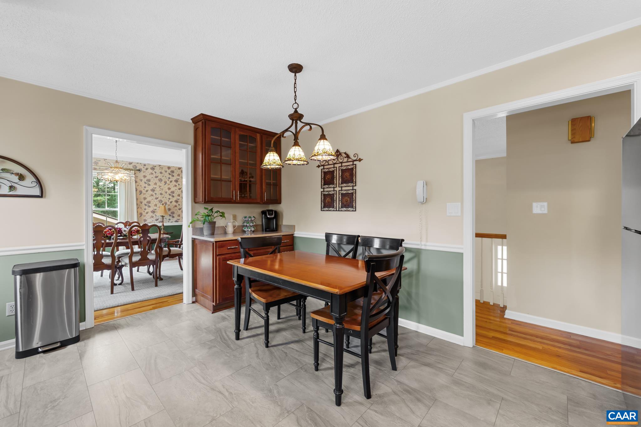 Enjoy versatile living in this open eat-in area! Highlights include stylish flooring, custom built-in cabinetry with a wet bar/coffee station, classic chair rail accents, and seamless transitions to the adjoining dining room and entryway!