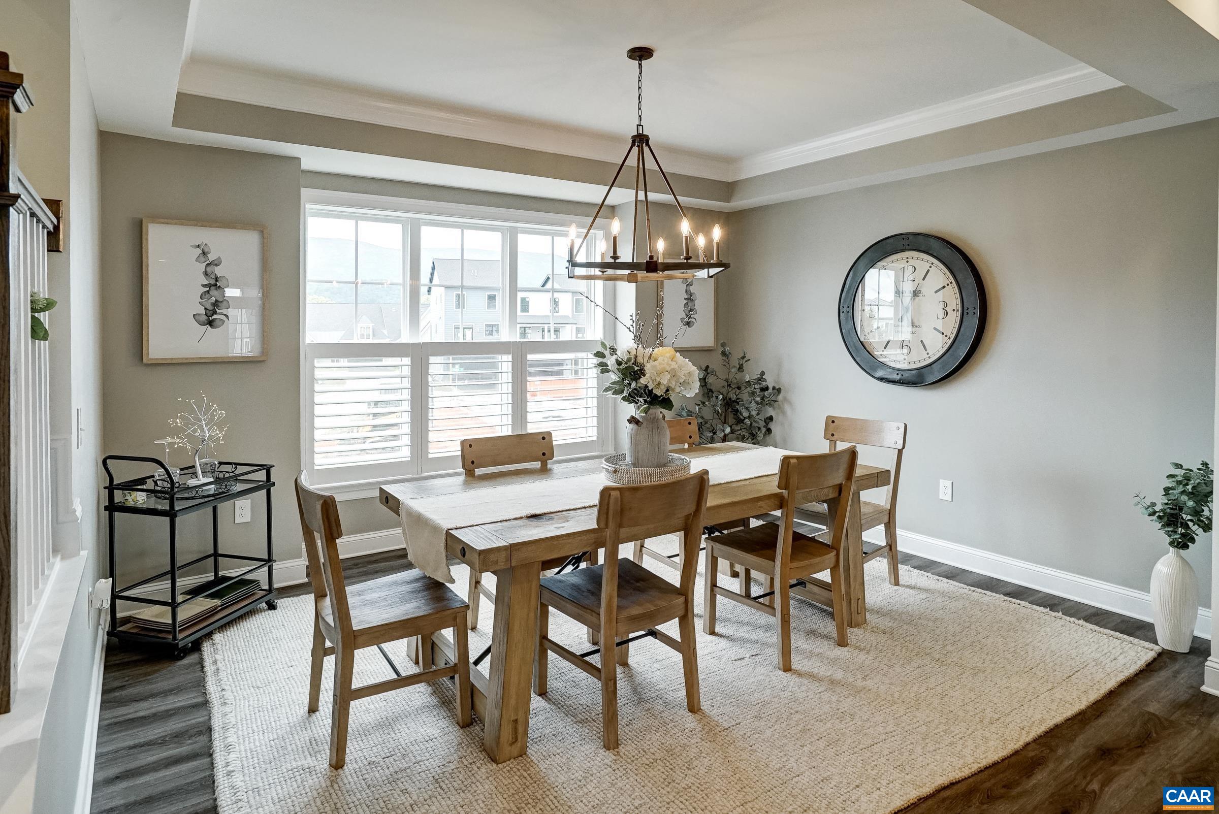 Dining room with tray ceiling and famhouse light.