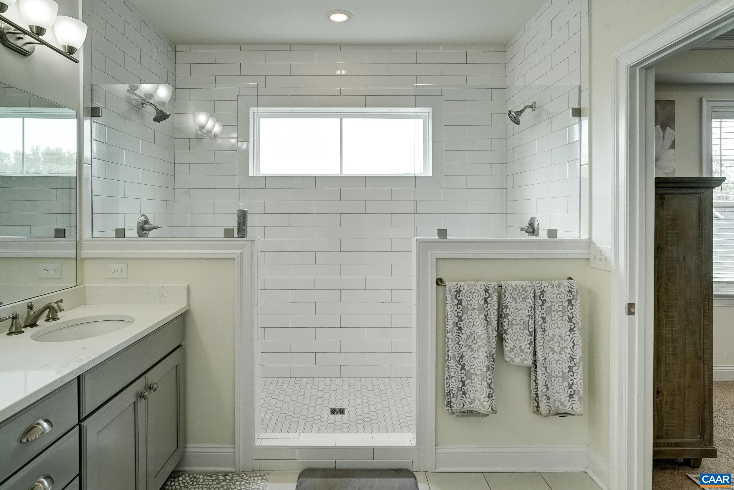 Frameless glass walk-in shower with two shower heads.