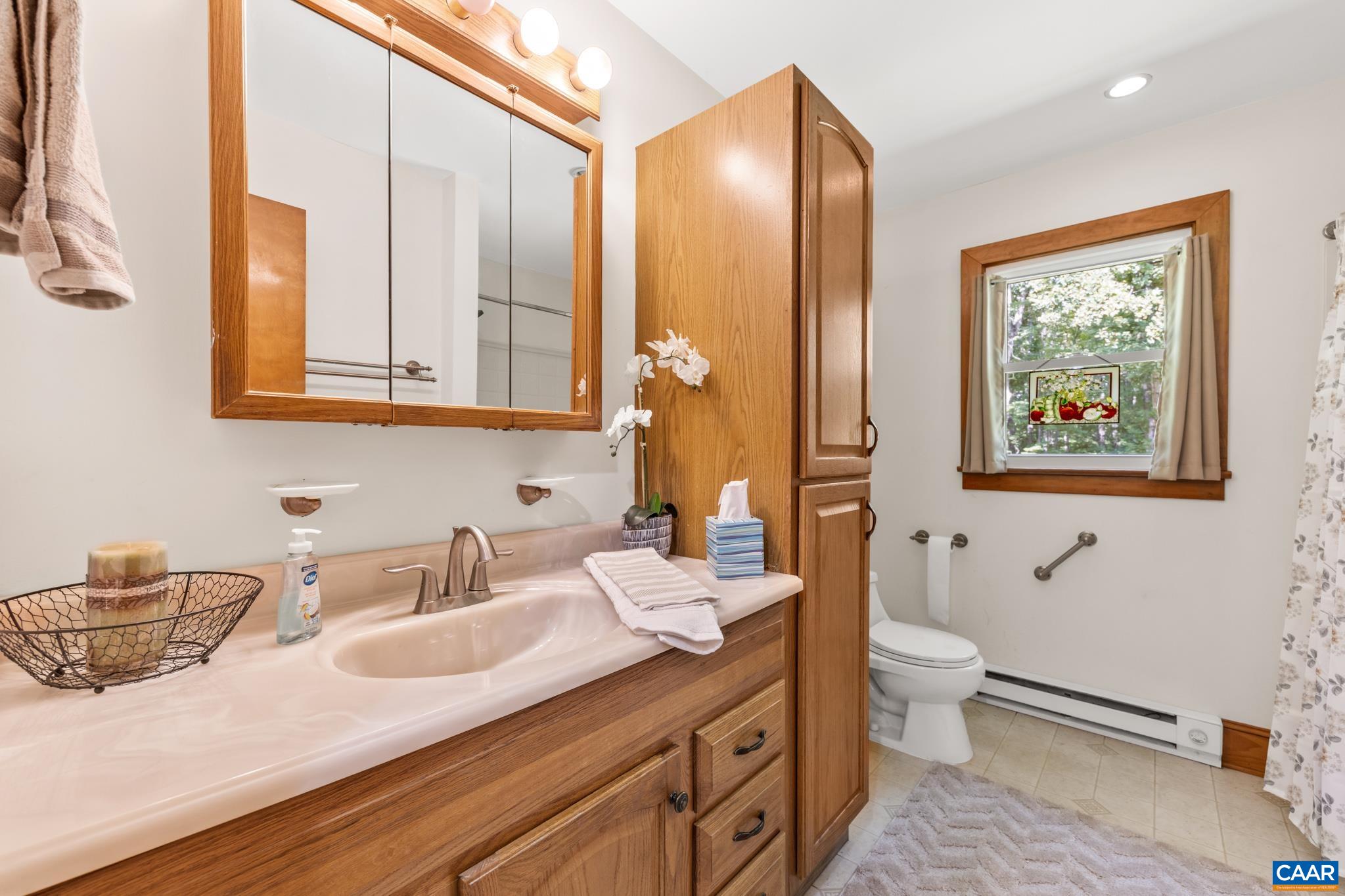 This bathroom offers generous counter space and a spacious linen closet for added storage.