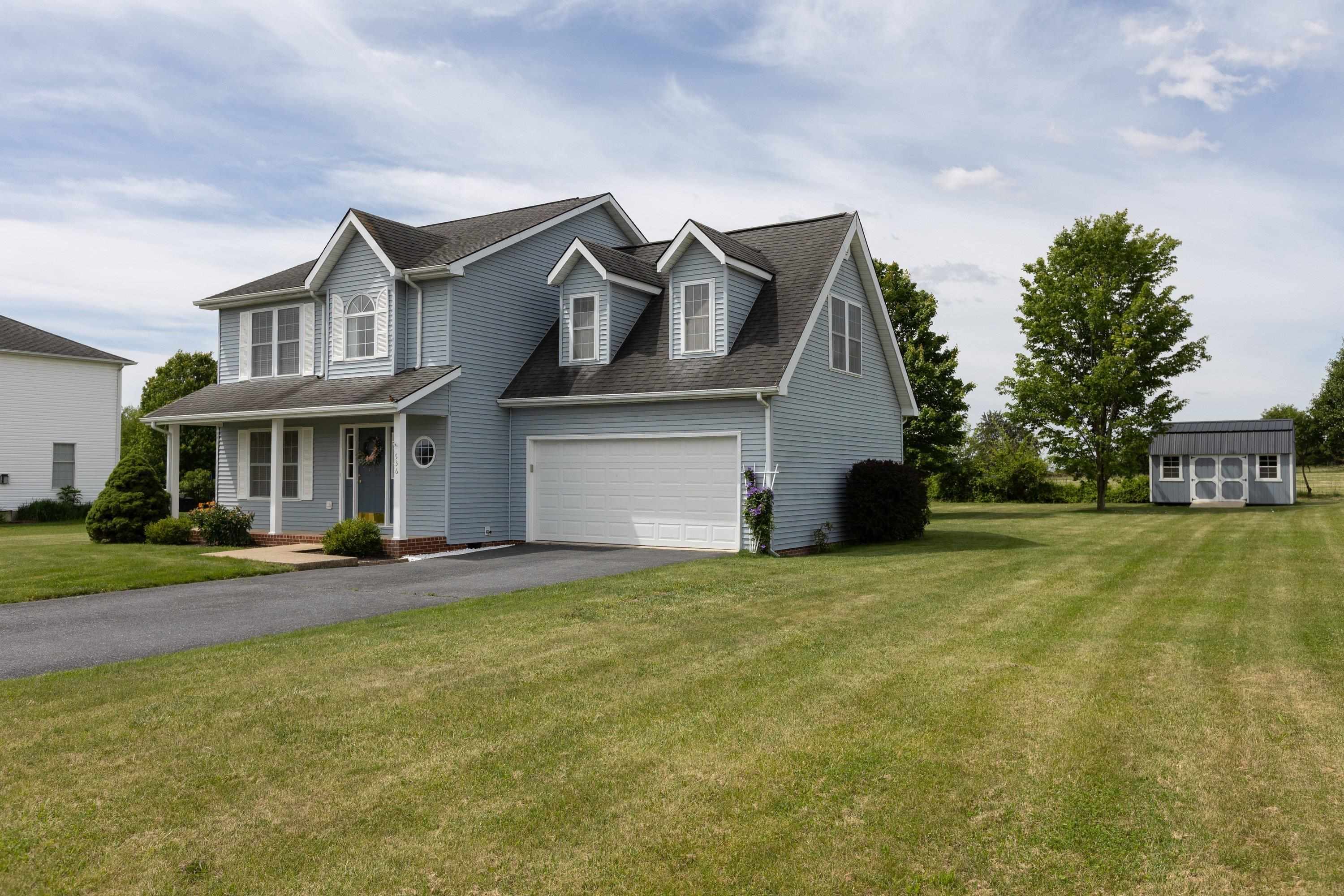 The front view of this home located in the Three Leagues subdivision highlights the two-car garage, front porch, large asphalt driveway, and landscaping. The front view of this home located in the Three Leagues subdivision highlights the two-car garage, front porch, large asphalt driveway, and landscaping.