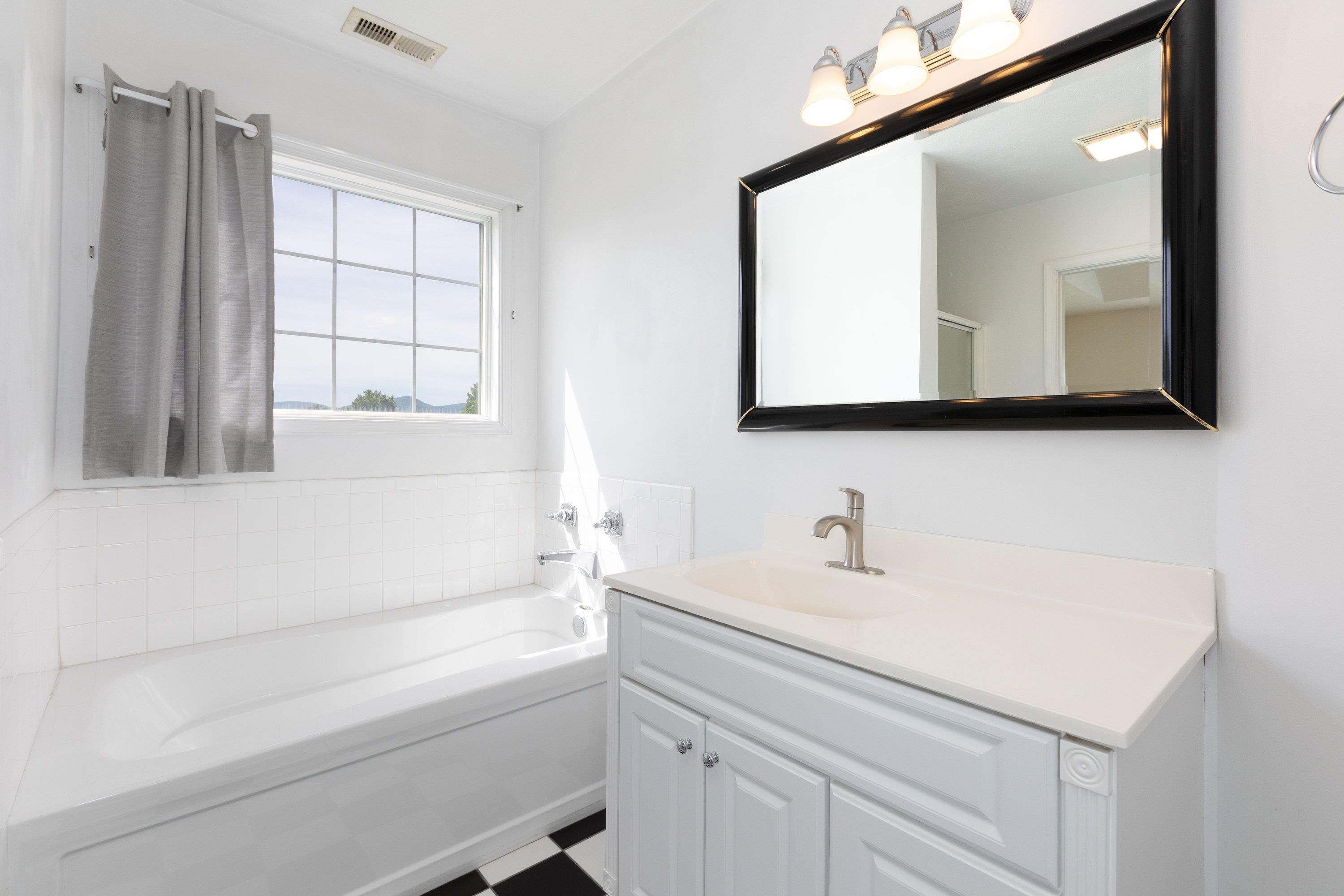 This full bathroom offers dual vanities and a vanity with storage. This space features tile flooring and a bathtub with walk-in shower space. This full bathroom offers dual vanities and a vanity with storage. This space features tile flooring and a bathtub with walk-in shower space.
