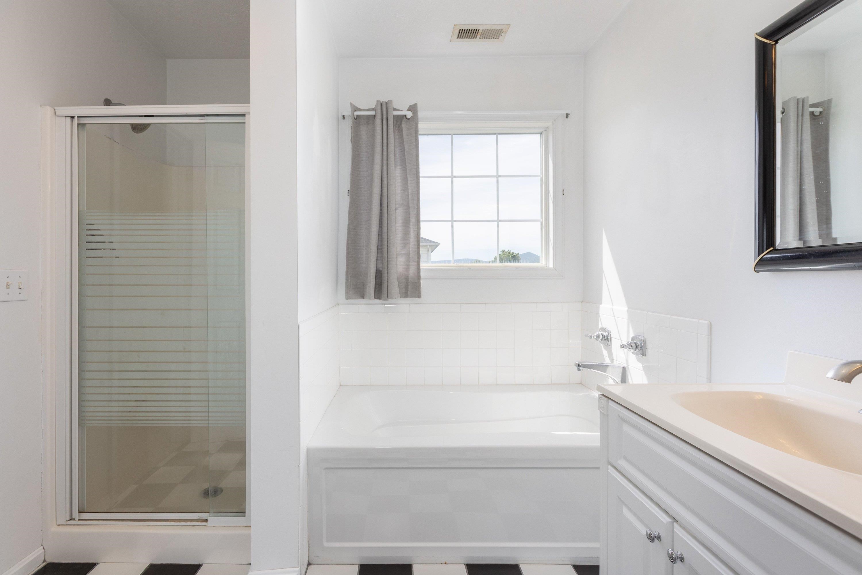 This full bathroom offers dual vanities and a vanity with storage. This space features tile flooring and a bathtub with walk-in shower space. This full bathroom offers dual vanities and a vanity with storage. This space features tile flooring and a bathtub with walk-in shower space.