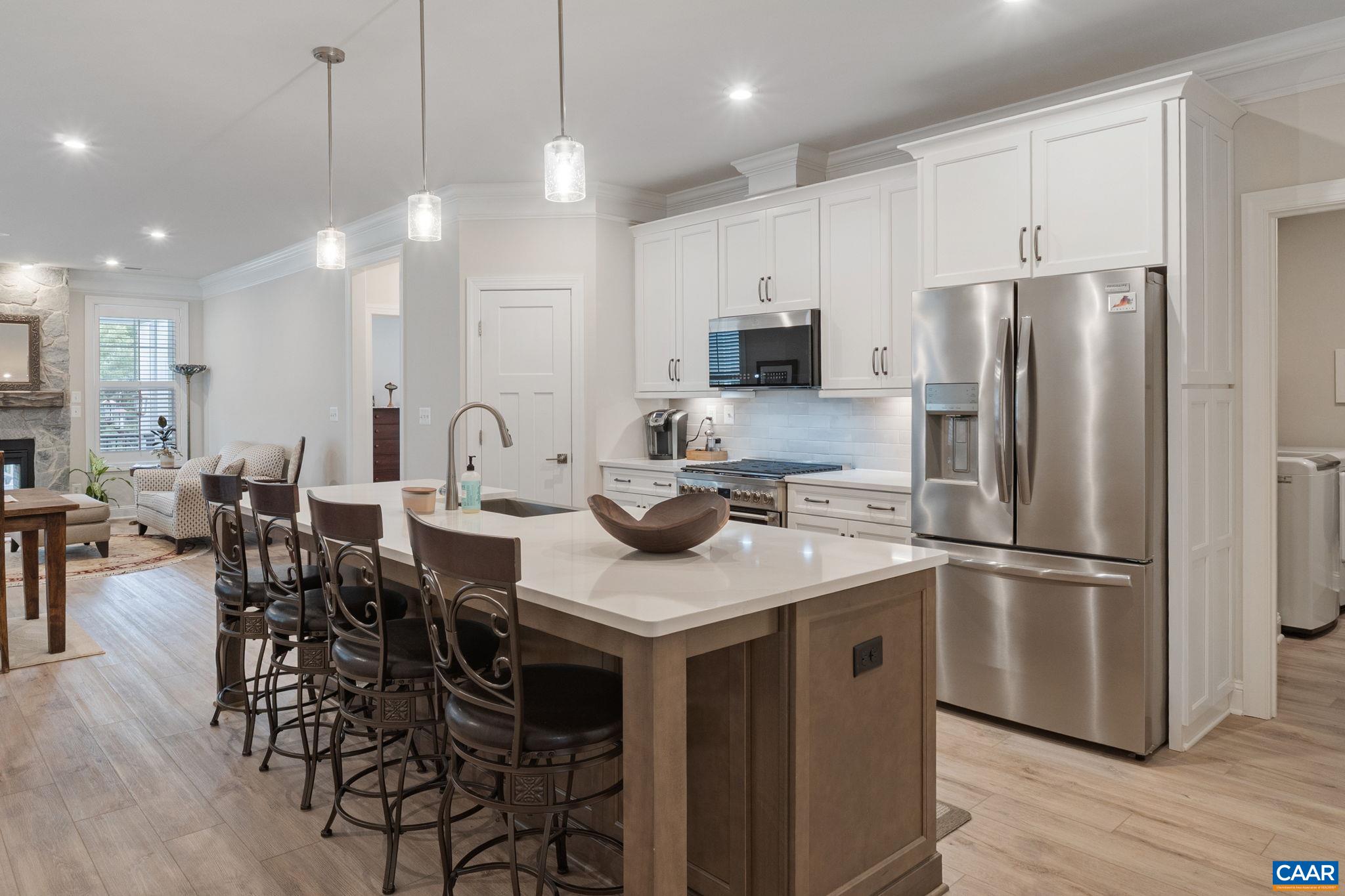 Chef's kitchen with large eating island, quartz counters, Electrolux stainless appliances, vented microwave/hood.