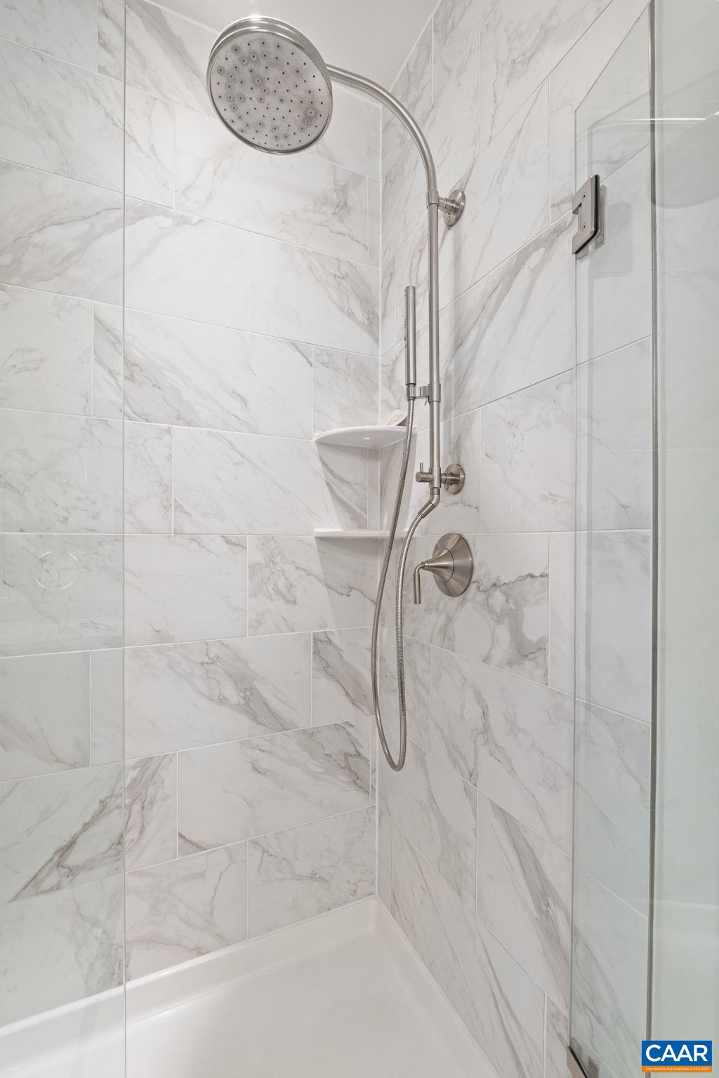 Tiled primary shower with hydrorail rain head and handheld wand.
