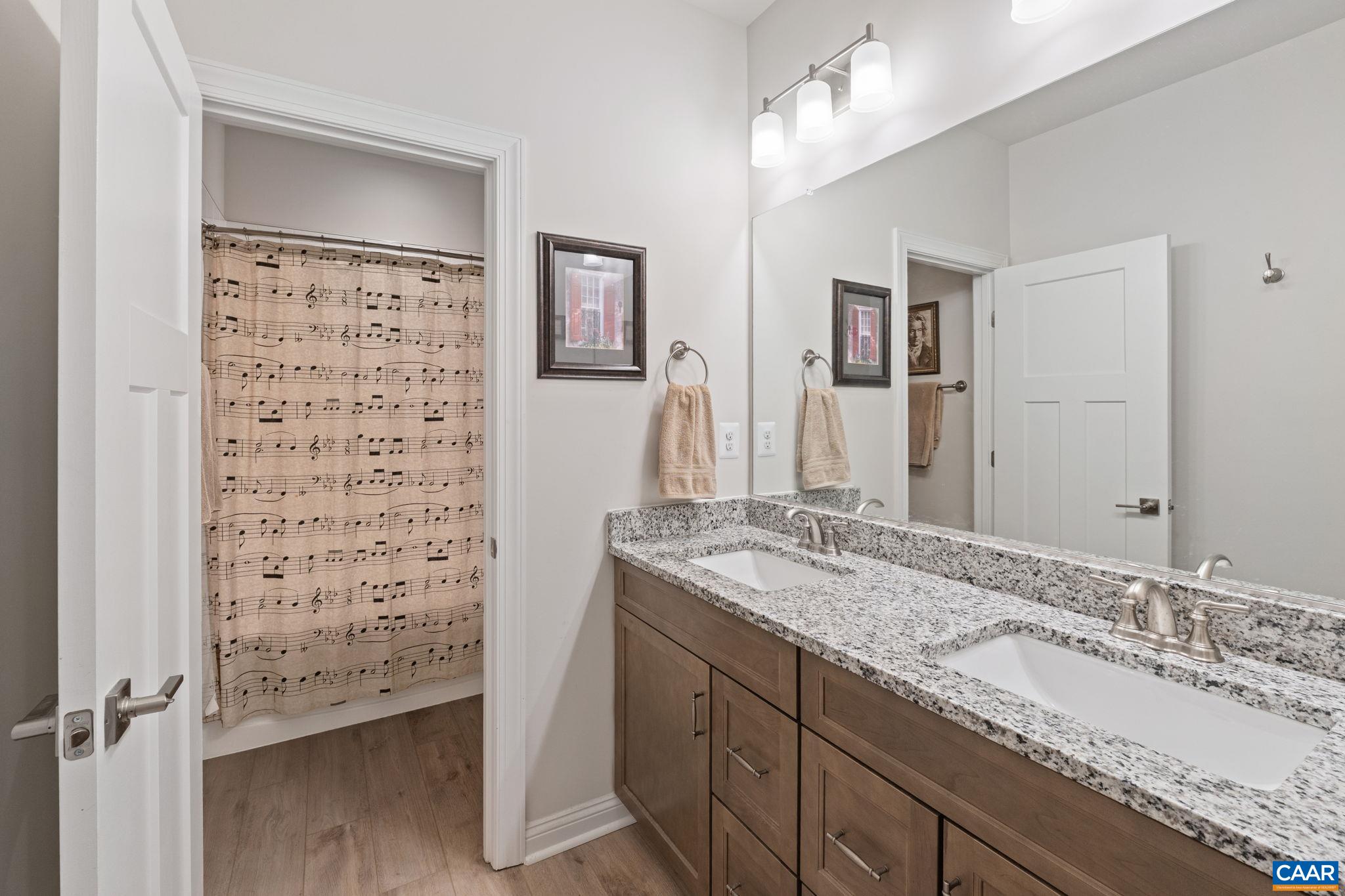 Fully tiled upstairs bathroom with double sink vanity and granite counter.