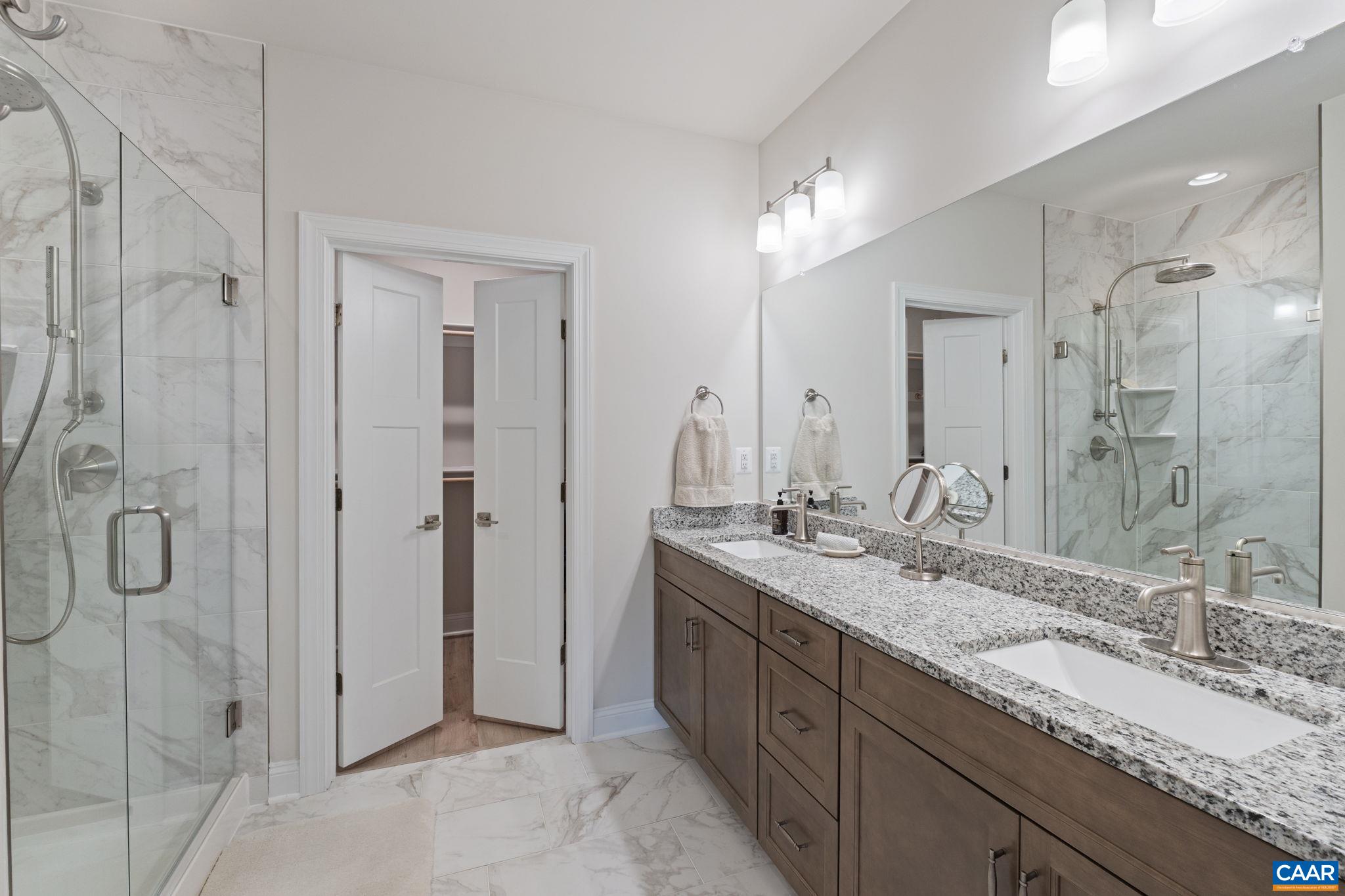 Fully tiled primary bath with double sink vanity and granite counters.