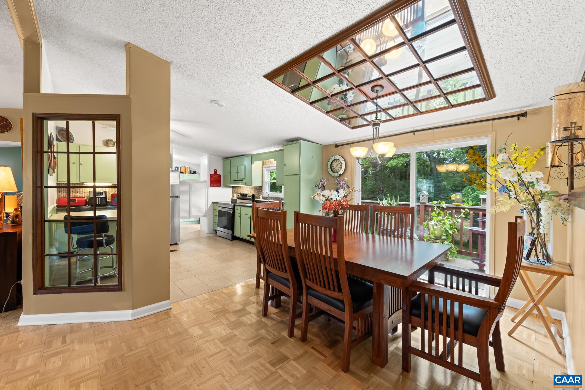 This open dining area features a decorative lighted ceiling accent, parquet floors, and direct access to a private back deck. Effortlessly connecting to the bright kitchen, it's a wonderfully inviting layout for hosting family and friends!