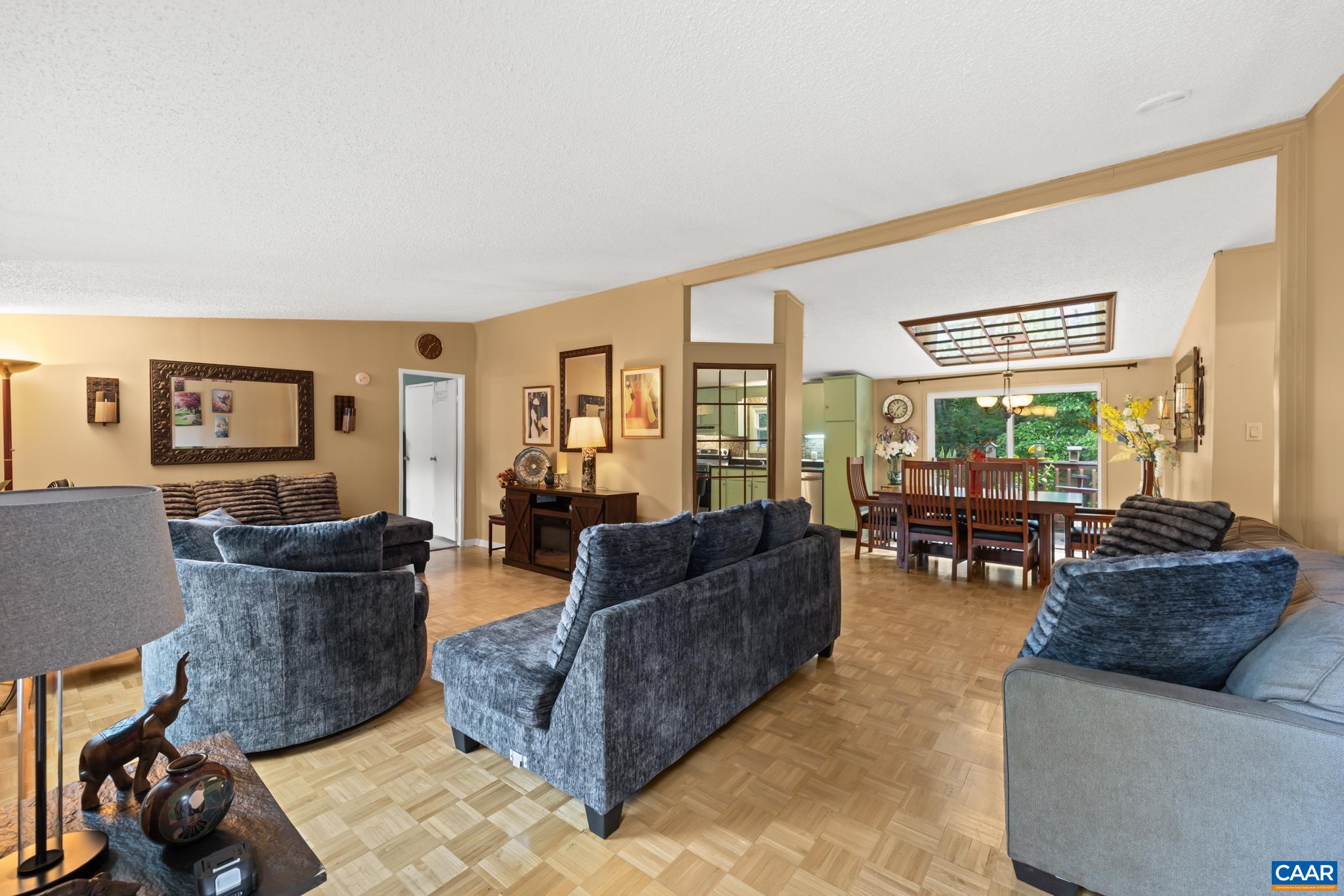 Step into warmth and comfort in this expansive living area! Featuring parquet flooring and rich natural tones, this inviting layout flows effortlessly into the dining room—perfect for relaxed everyday living and effortless entertaining.