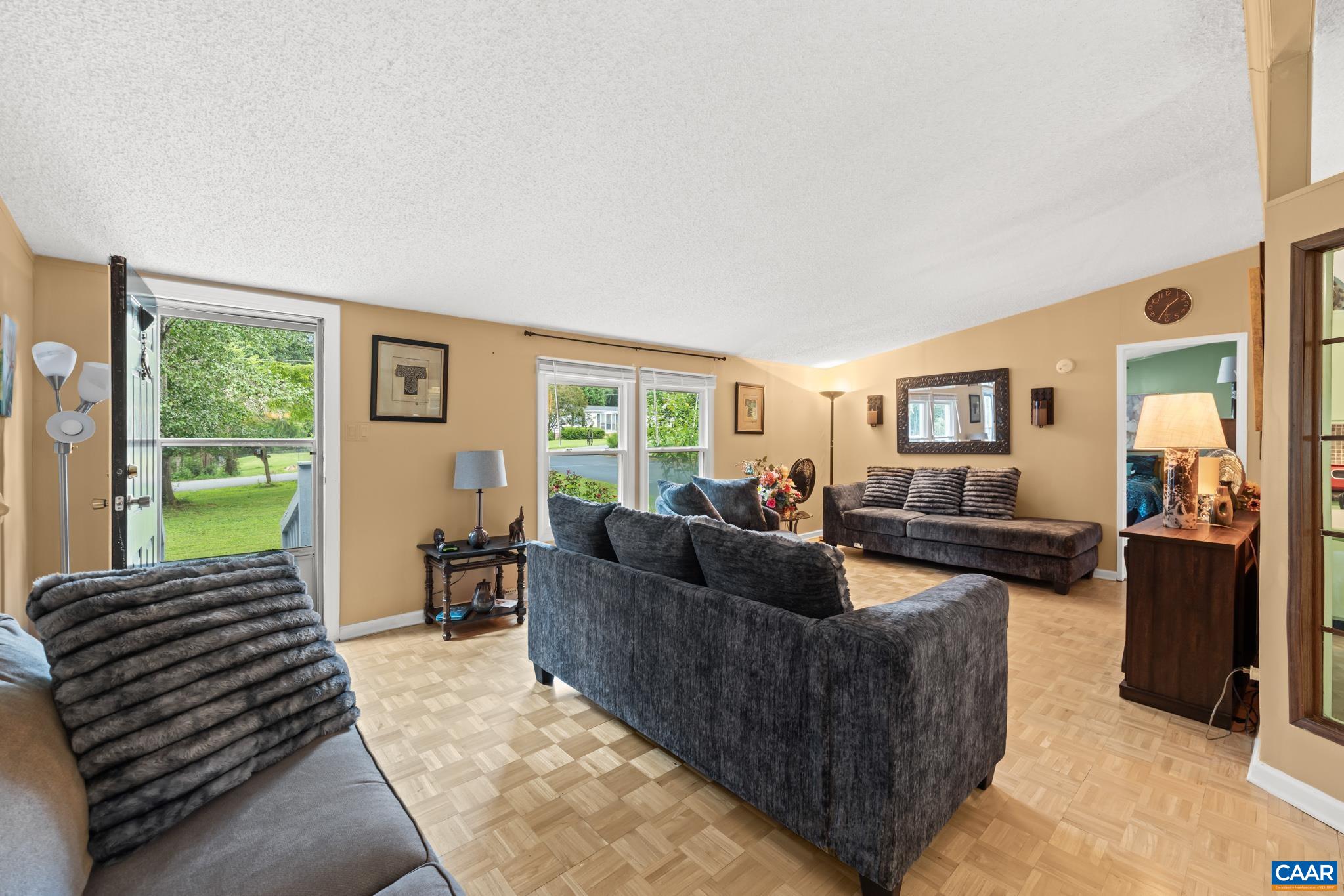 Welcome guests into a bright, airy foyer and living room! Featuring classic parquet flooring, generous natural light, and tranquil views of greenery through large glass doors, this versatile space is perfect for daily living and entertaining.