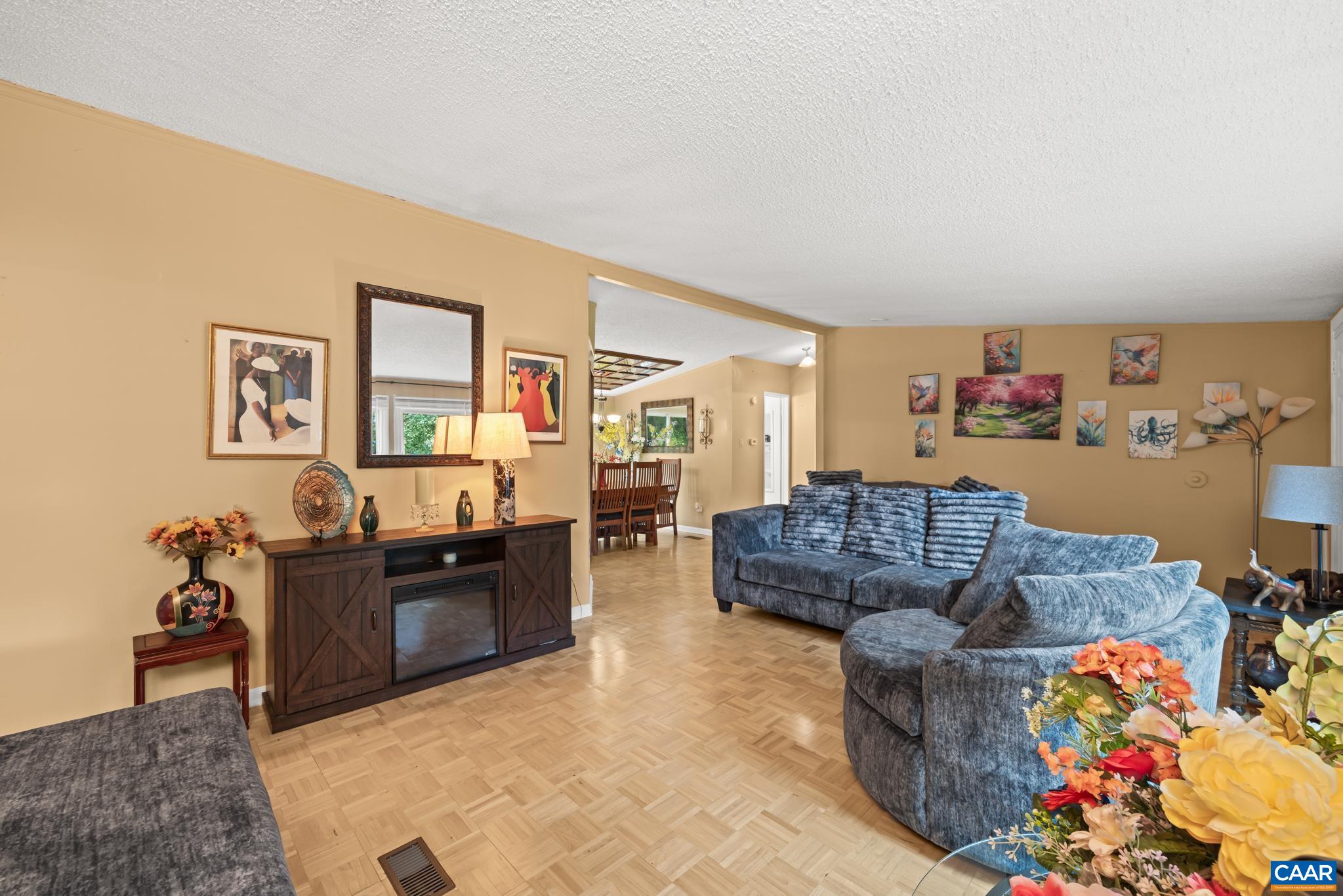 Spacious living room designed for ultimate relaxation and entertaining! Highlights classic parquet flooring, warm neutral tones, ample cozy seating, and a large media console. Opens seamlessly to the dining room for a natural, flowing layout.