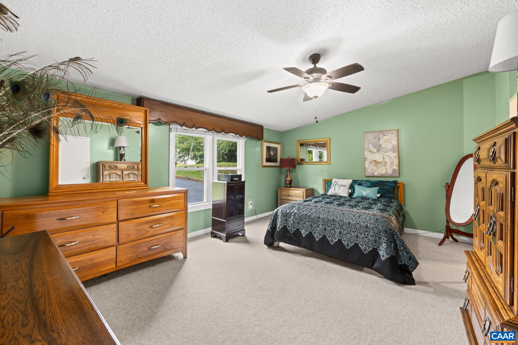 Spacious bedroom retreat featuring tranquil sage green walls, plush carpet, and bright double windows! Complete with a ceiling fan and generous layout with ample room for full furniture sets, it offers a soothing space to unwind.