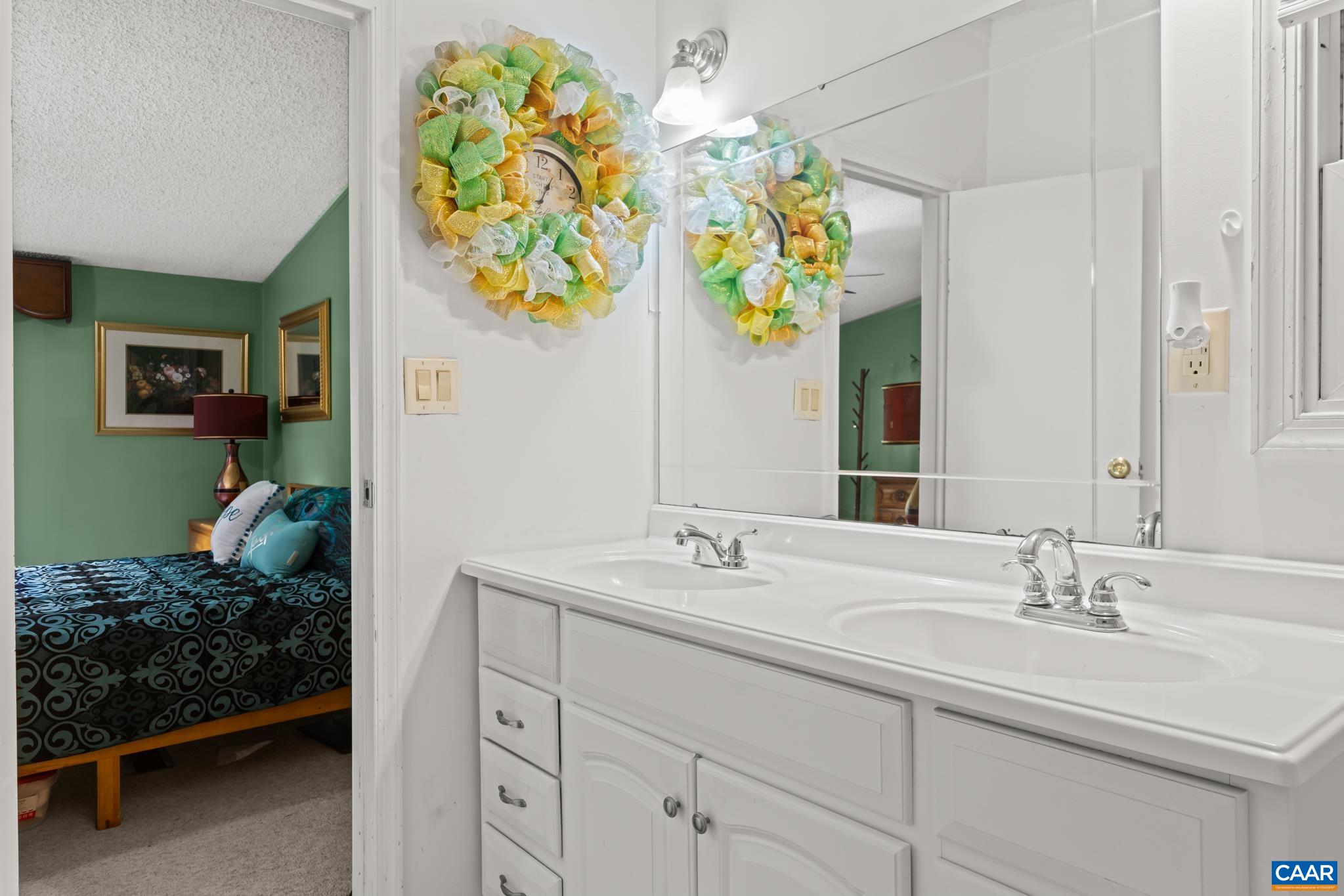 Bright and spacious double-sink vanity in a primary bath setup! Generous counter space and cabinet storage make morning routines effortless, with seamless adjoining access to a cozy, sunlit bedroom. Clean, functional, and conveniently located!