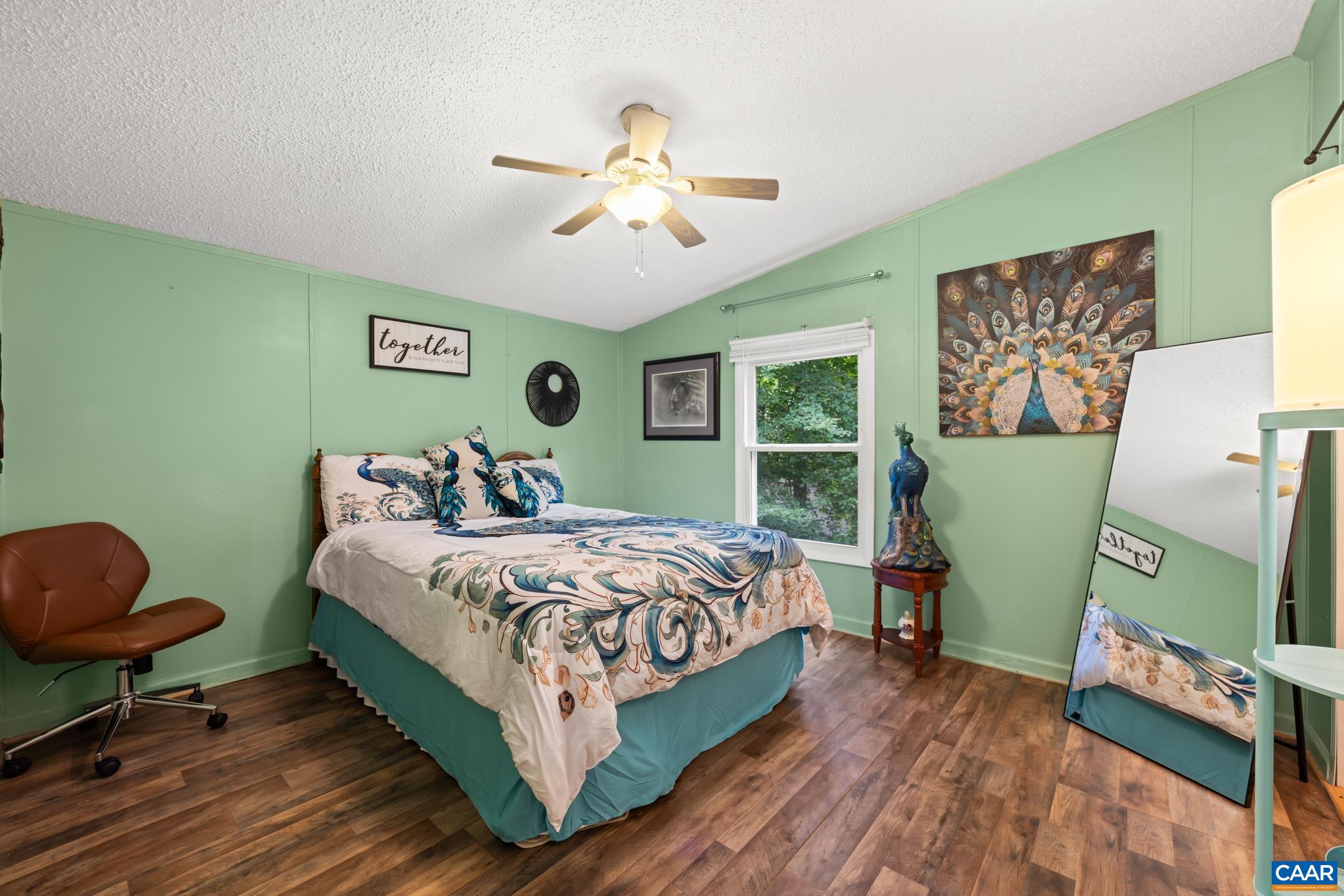Charming third bedroom featuring soft sage green walls, stylish wood-look flooring, and bright natural light! Complete with a ceiling fan and generous space for furnishings, this cozy room makes a delightful guest room, nursery, or office space.