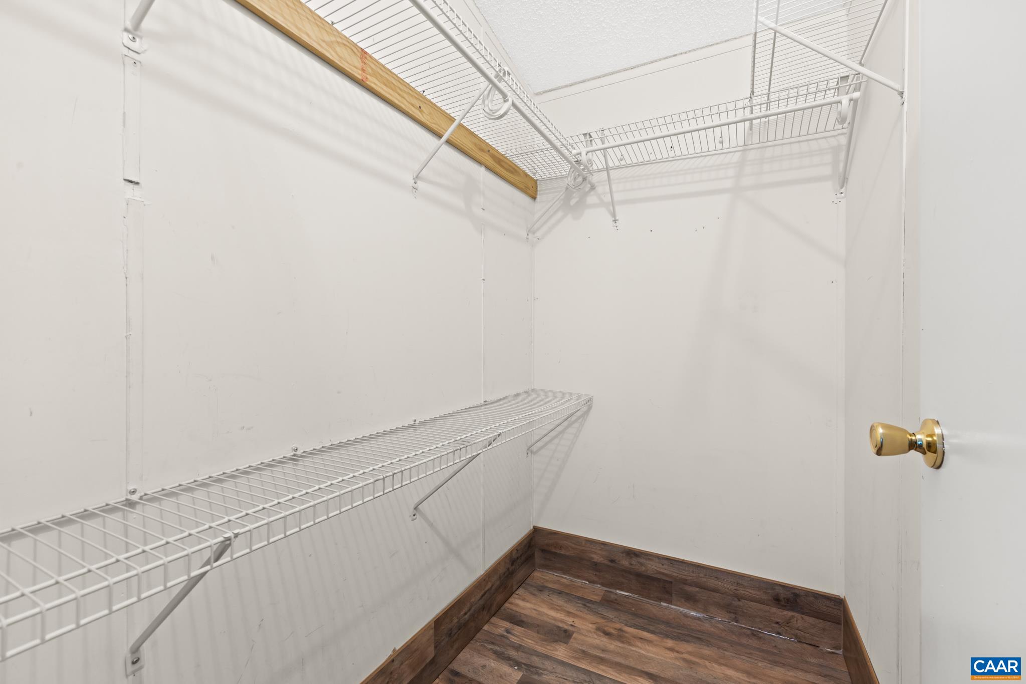 Generous walk-in closet featuring built-in wire shelving for maximized storage and easy organization! Complete with stylish wood-look flooring, it offers plenty of space to keep clothes, accessories, and everyday essentials neatly arranged.