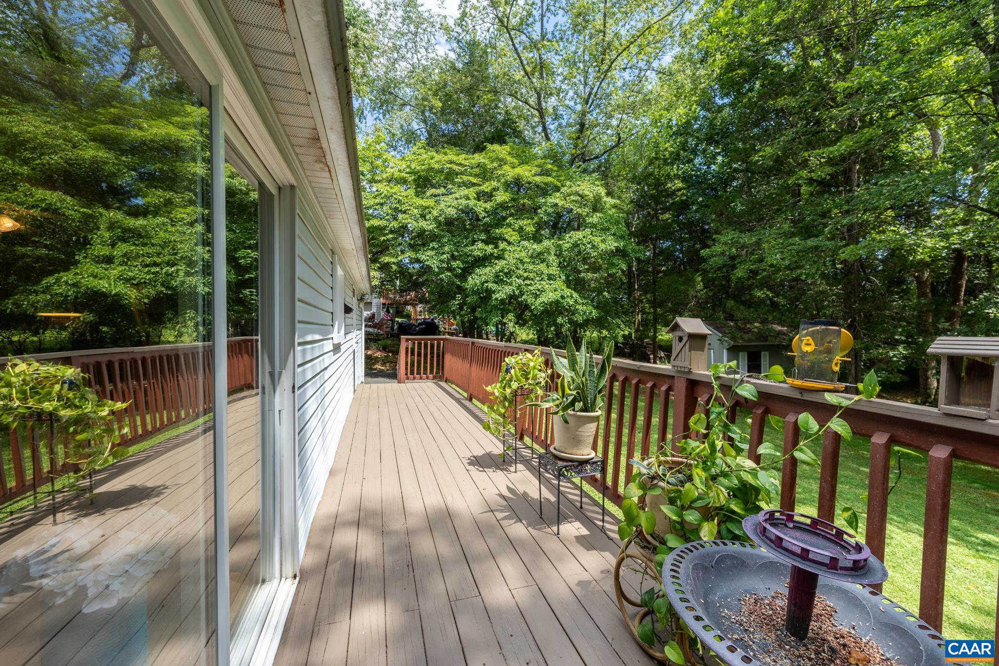 Relax on your private, spacious back deck! Overlooking a lush, wooded yard, this peaceful outdoor space features wooden railings, sliding glass door access, and plenty of room for potted plants and outdoor lounging. Perfect for outdoor living!