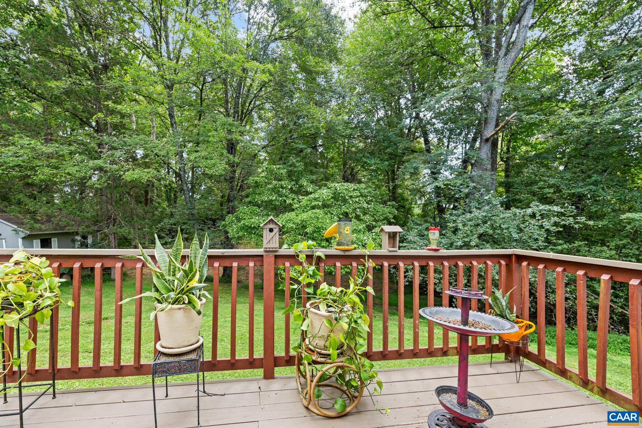 Enjoy peaceful outdoor living on this charming back deck! Featuring warm wooden railings, potted plants, a bird bath, and lush tree-lined backdrop, this serene oasis is perfect for relaxing, entertaining, and taking in nature right at home.