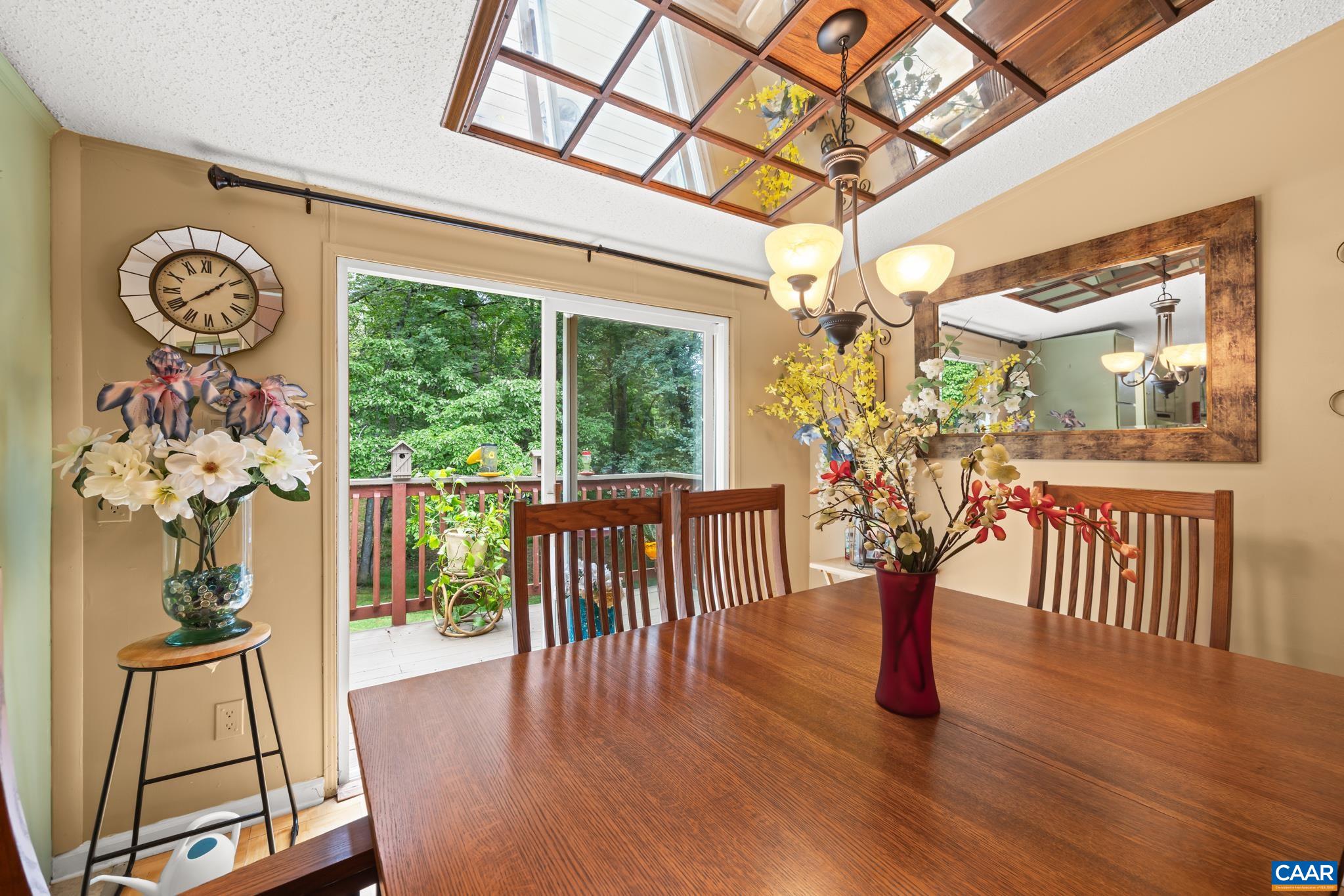 Gather in comfort in this charming dining space! Showcasing a unique decorative ceiling accent, warm wood tones, and sliding doors opening to a scenic back deck, it offers a seamless blend of cozy indoor dining and peaceful outdoor views.