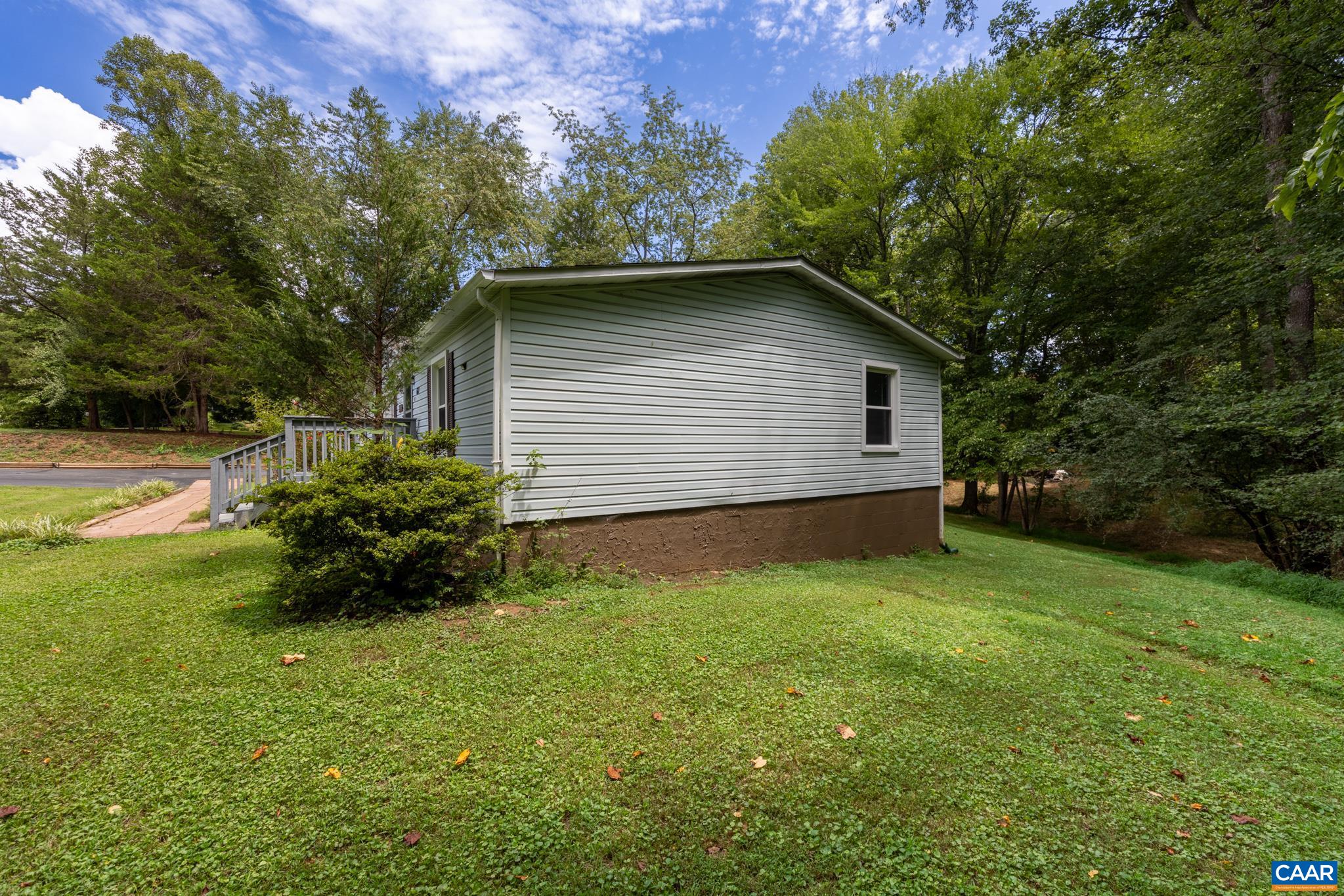 Peaceful and private outdoor setting! Surrounded by mature trees and lush green lawns, this charming home feature light siding, a spacious yard, and a serene, woodsy backdrop—ideal for enjoying quiet moments and nature right at home.