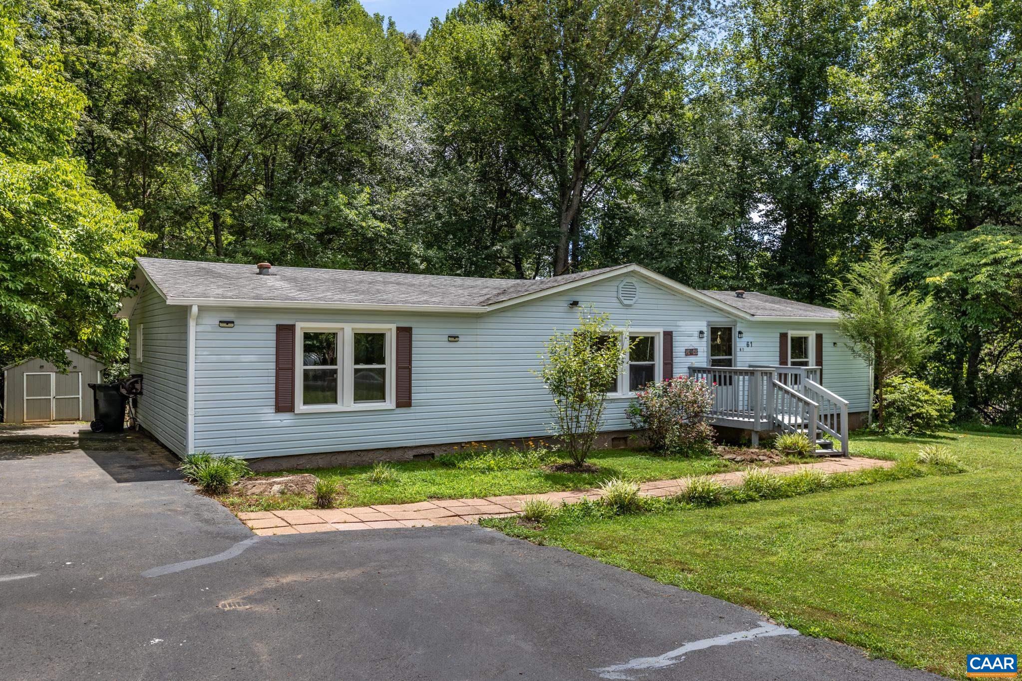 Charming single-story home nestled in a peaceful, tree-lined setting! Features clean siding, dark accent shutters, a paved driveway, and a welcoming front porch. Surrounded by a lush lawn and garden beds, it offers quintessential curb appeal!