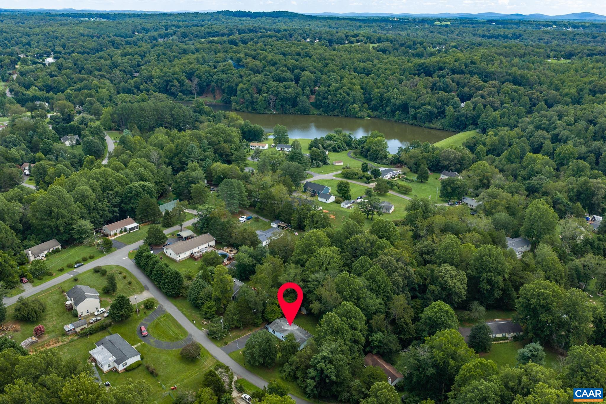 Prime location pinpointed in a idyllic neighborhood setting! This aerial photo shows proximity to local roadways, a quiet residential community, lush surrounding greenery, and a nearby lake. The perfect combination of convenience and nature!