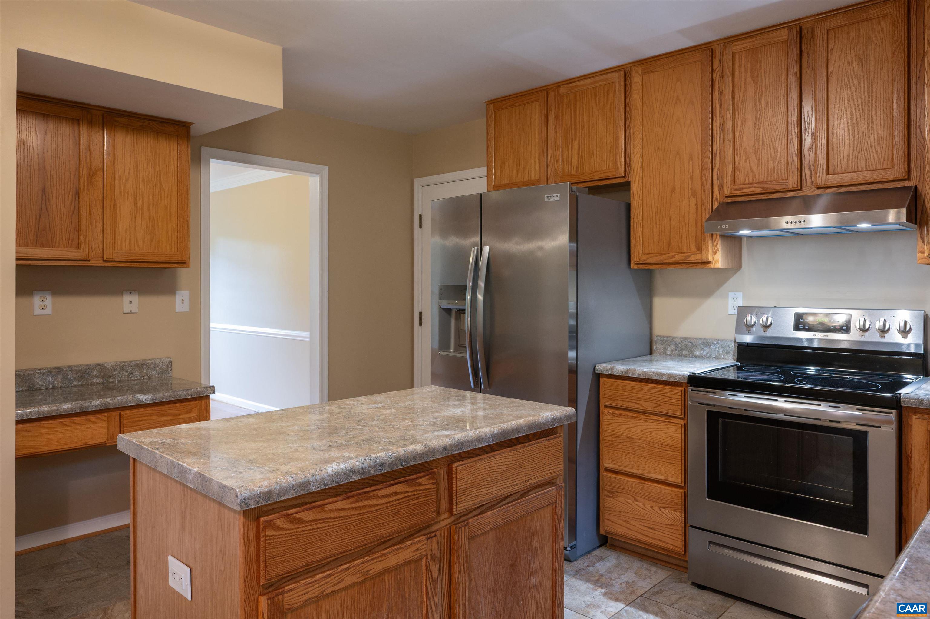 The kitchen features stainless appliance, desk area, island and pantry.