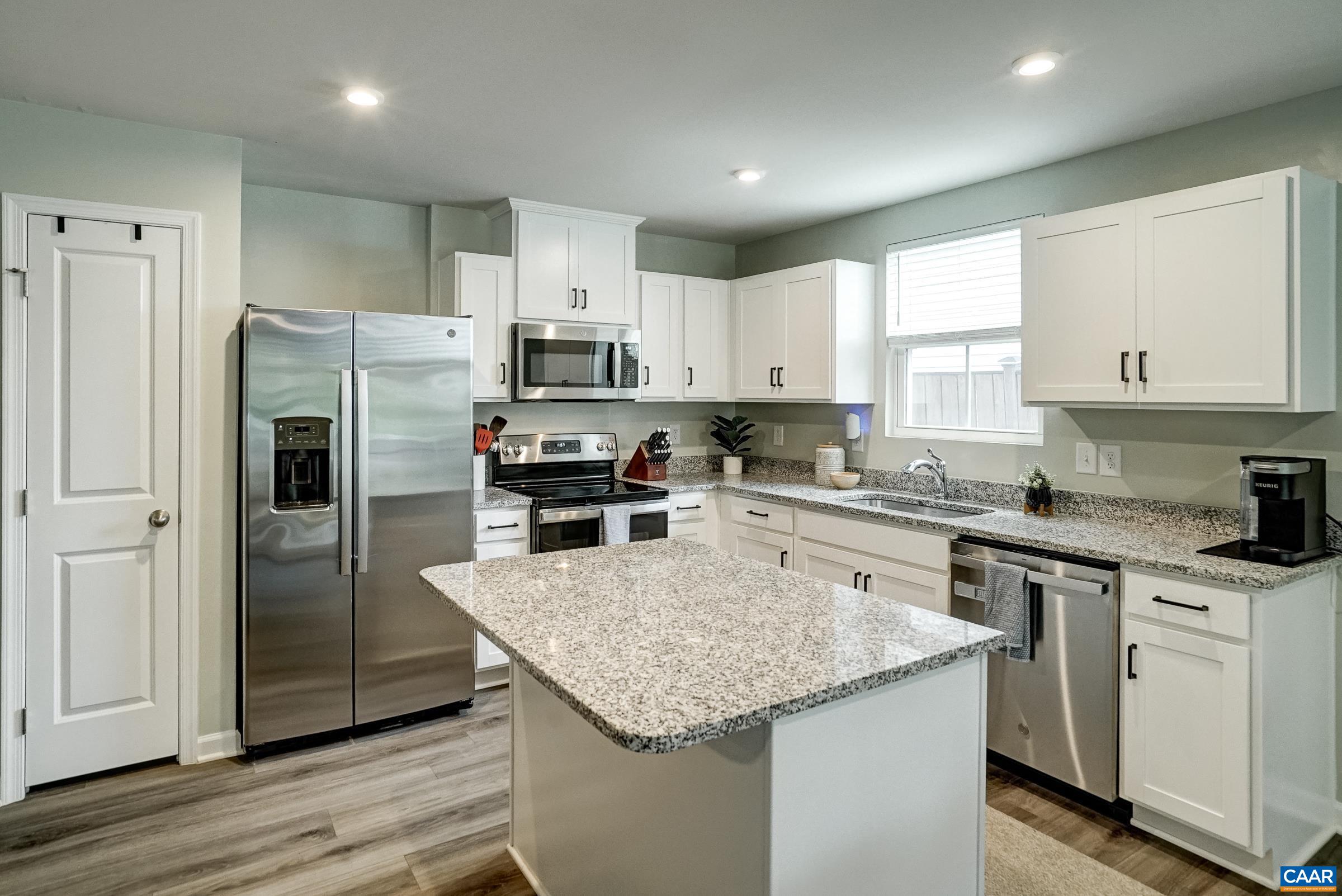 Modern kitchen with white cabinets, granite island and stainless appliances Modern kitchen with white cabinets, granite island and stainless appliances