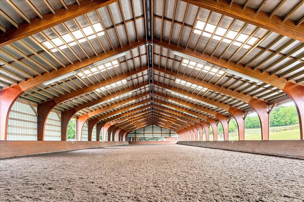 Approximately 14,400 sq. ft., with an additional 4' overhang. Constructed in 2005, the arena features a laminated wood beam structure with aluminum siding along one long wall and one end wall. The riding surface consists of crusher run/sand/Trutex Approximately 14,400 sq. ft., with an additional 4' overhang. Constructed in 2005, the arena features a laminated wood beam structure with aluminum siding along one long wall and one end wall. The riding surface consists of crusher run/sand/Trutex