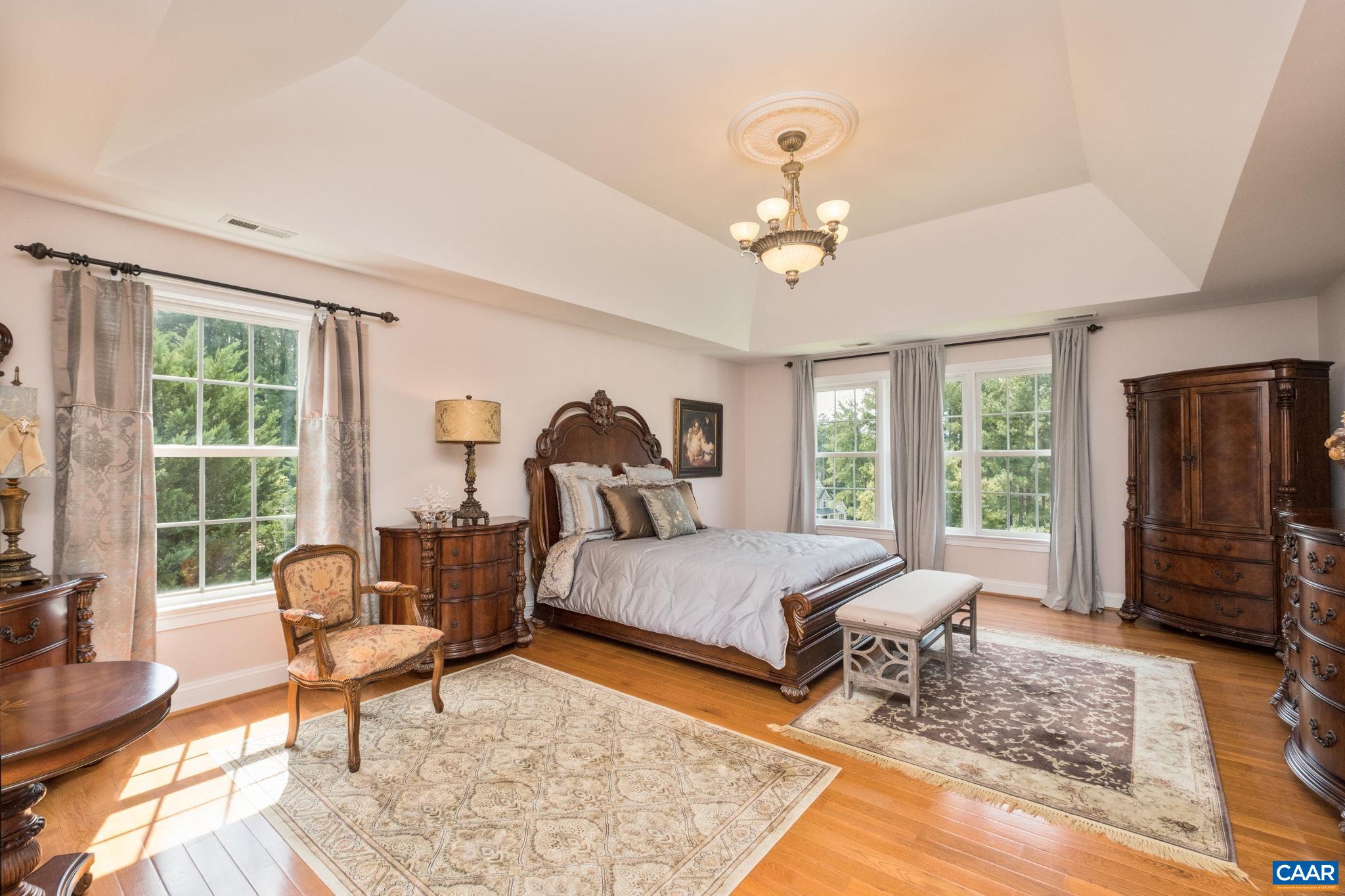 The primary suite features a sitting area, a tray ceiling with a ceiling medallion, and windows for natural light. Hardwood flooring continues throughout the home. The primary suite features a sitting area, a tray ceiling with a ceiling medallion, and windows for natural light. Hardwood flooring continues throughout the home.