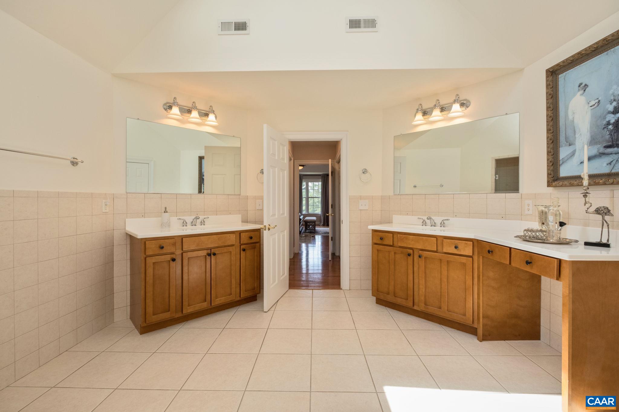 This view is from the primary bathroom looking toward the bedroom. The hallway features closets on both sides, and one closet is a walk-in closet. Skylights with shades are in the bathroom. Bathroom features dual sinks and a vanity area. This view is from the primary bathroom looking toward the bedroom. The hallway features closets on both sides, and one closet is a walk-in closet. Skylights with shades are in the bathroom. Bathroom features dual sinks and a vanity area.