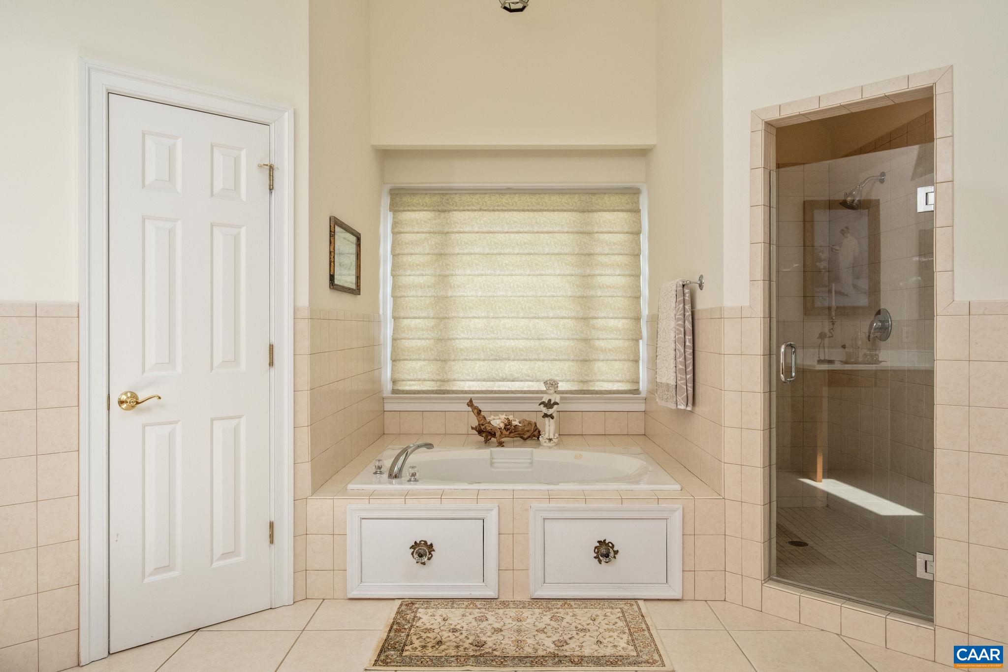 The water closet is to the left, and the walk-in tiled shower is to the right of the tub. The water closet is to the left, and the walk-in tiled shower is to the right of the tub.