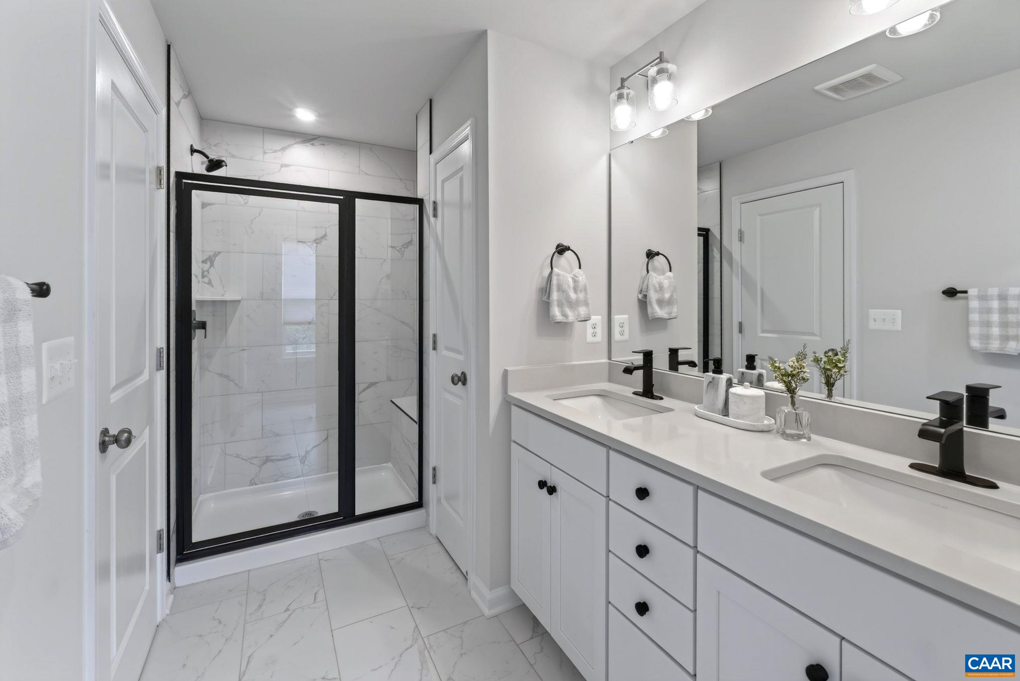The primary bath features a separate water closet, linen closet, double vanity, and spacious tiled shower with bench seating The primary bath features a separate water closet, linen closet, double vanity, and spacious tiled shower with bench seating