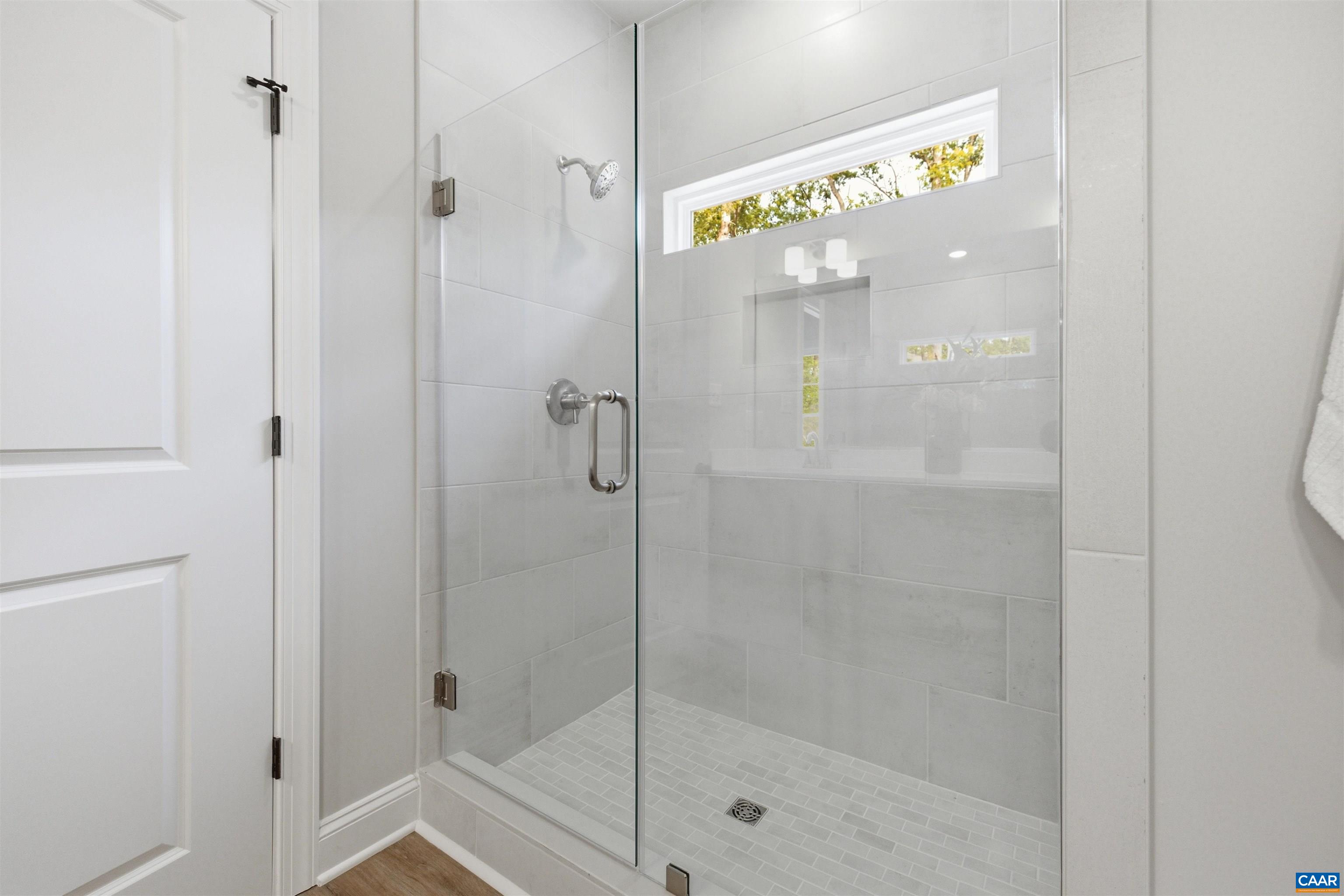 Tile to the ceiling, transom window and frameless glass door. Photo of for-sale home, staged.